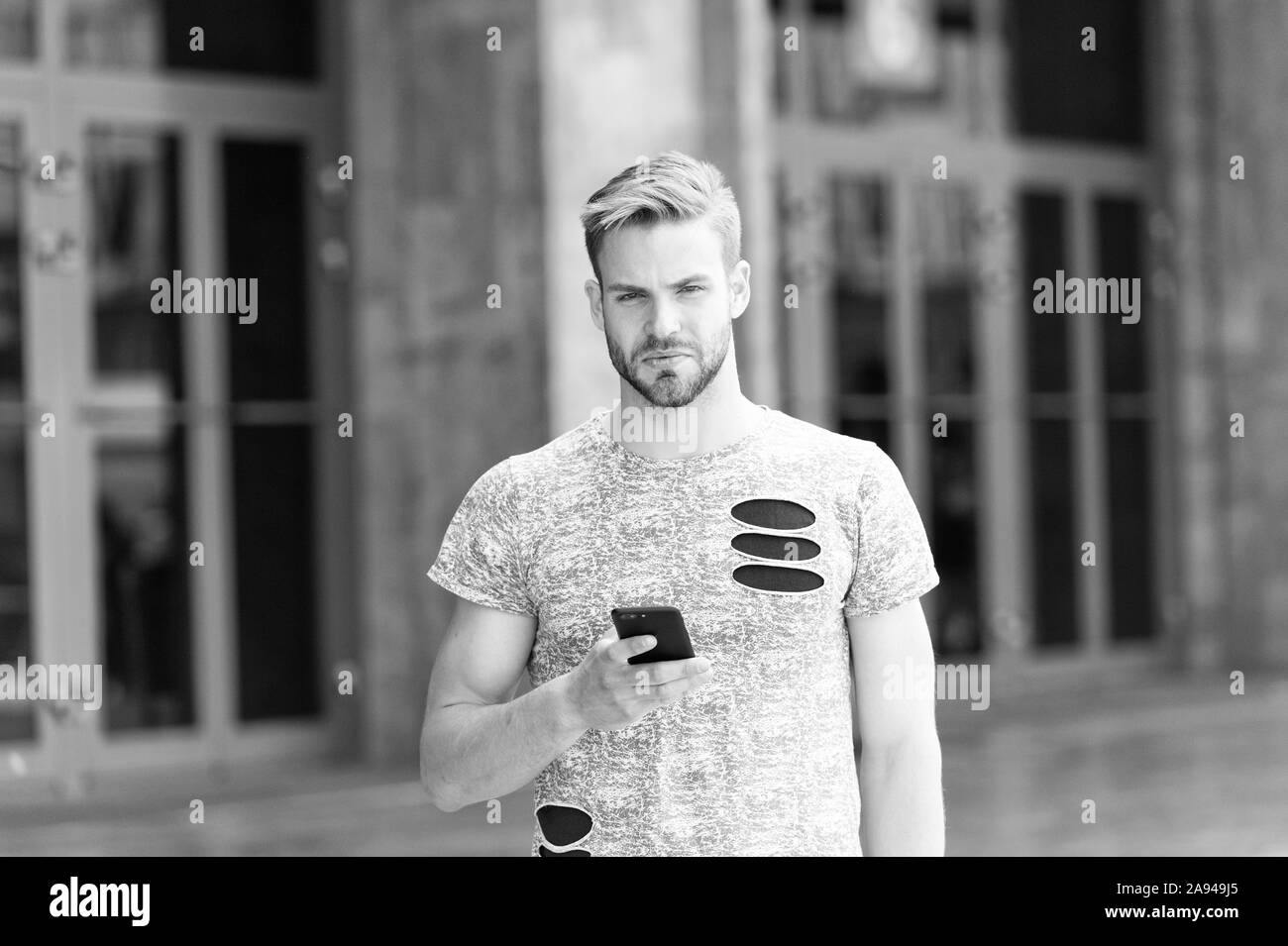 Style de vie mobile. Guy de race blanche à l'aide de téléphone mobile à l'extérieur. Bel homme avec un appareil mobile dans la main on city street. L'homme élégant bénéficiant d'internet mobile pour la messagerie texte et les appels vidéo. Banque D'Images