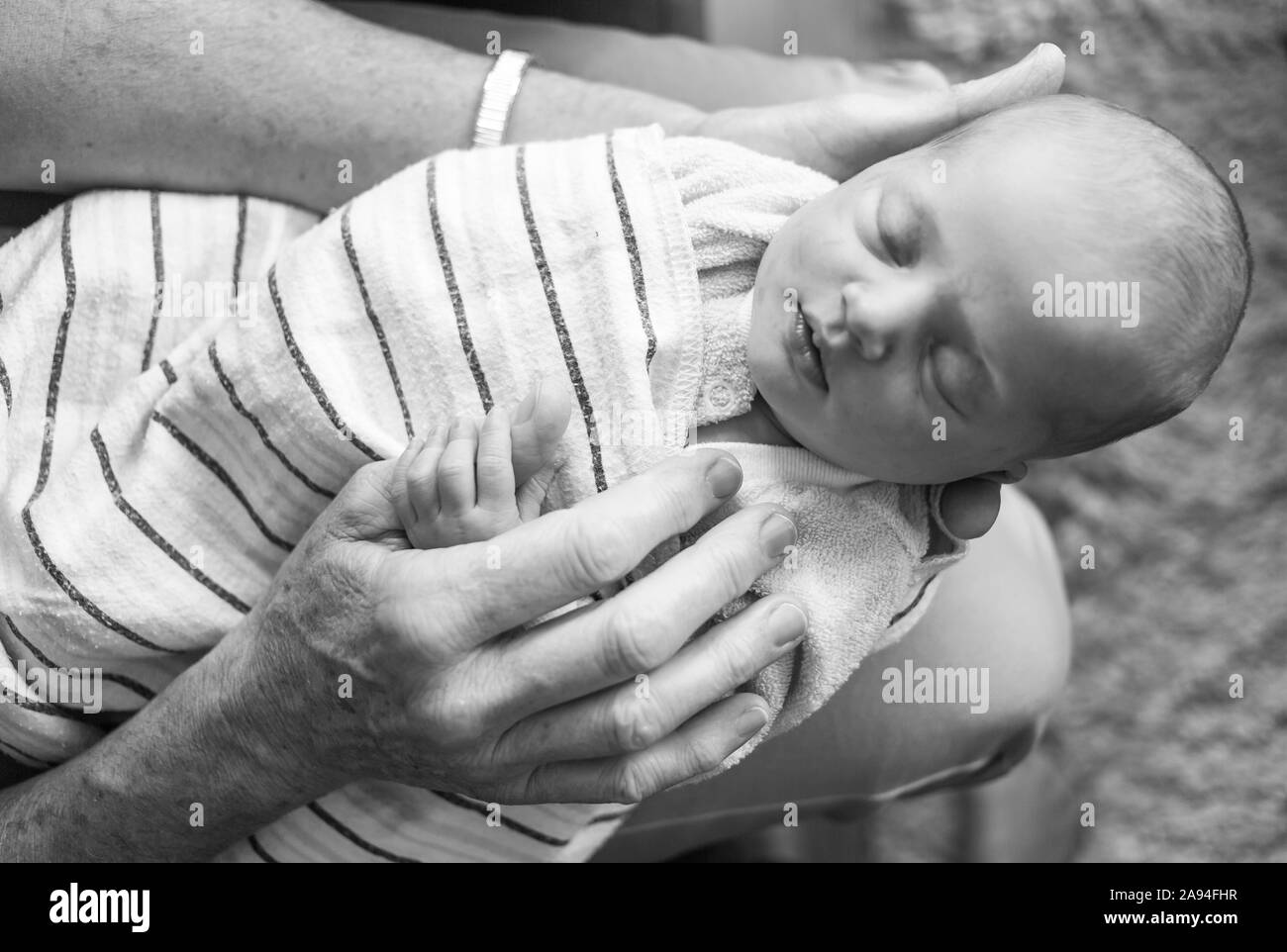 Jeune fille de nouveau-né enveloppée dans une couverture et dormant sur les genoux de son père; Vancouver, Colombie-Britannique, Canada Banque D'Images