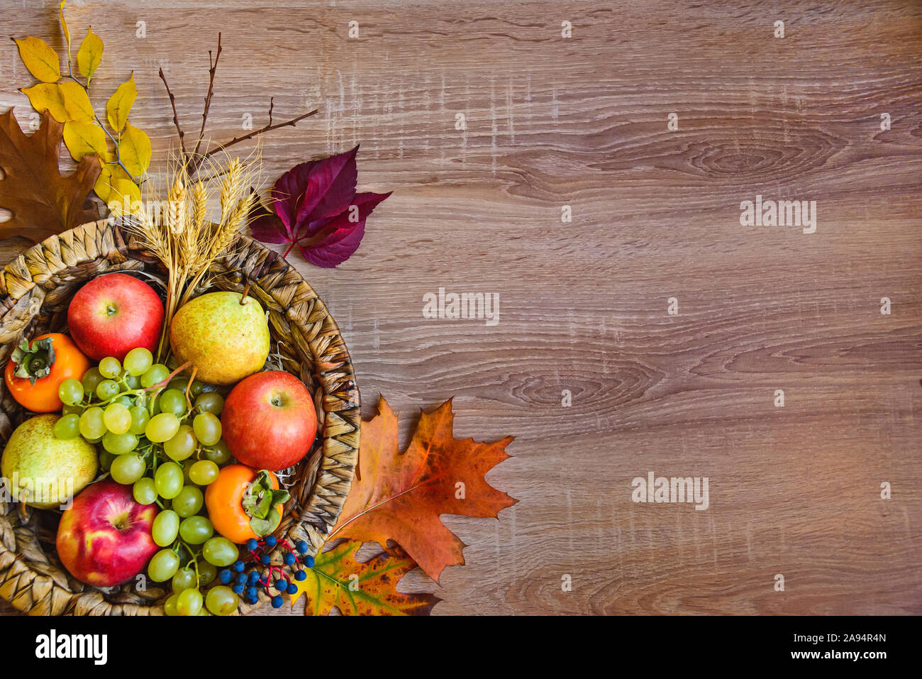 Vue de dessus de divers fruits d'automne et de feuilles dans un panier en osier sur la table en bois. Copier l'espace. Banque D'Images