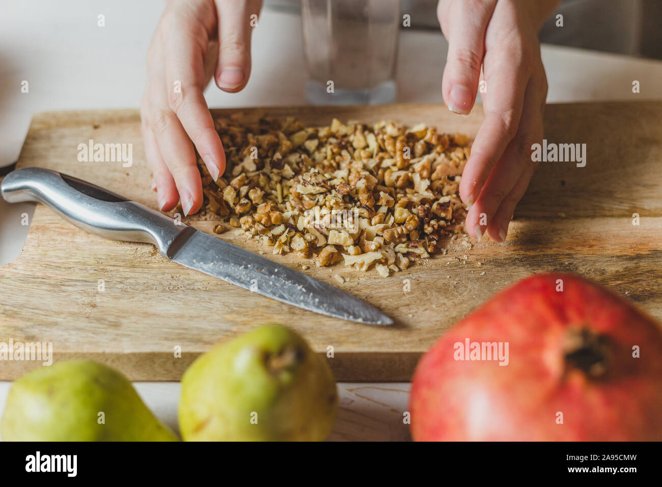 Mains d'une jeune fille rurale la préparation poire fait maison, de grenade, canneberge, noyer, épinards et fromage salade - cuisine maison Banque D'Images