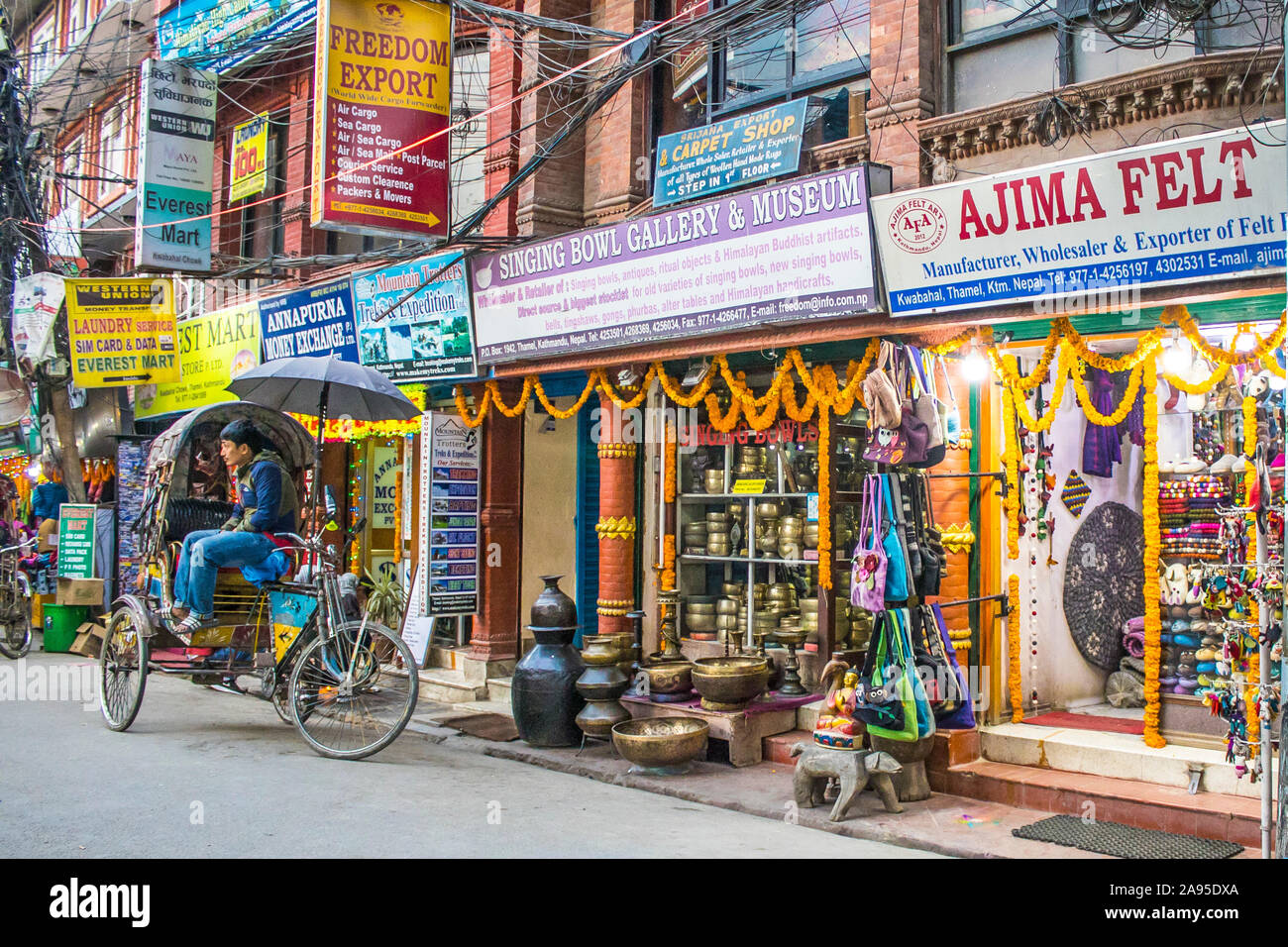 Un extracteur de pousse-pousse en attente de client dans l'avant du magasin qui vend des bols tibétains dans la région touristique de Thamel à Katmandou. Banque D'Images