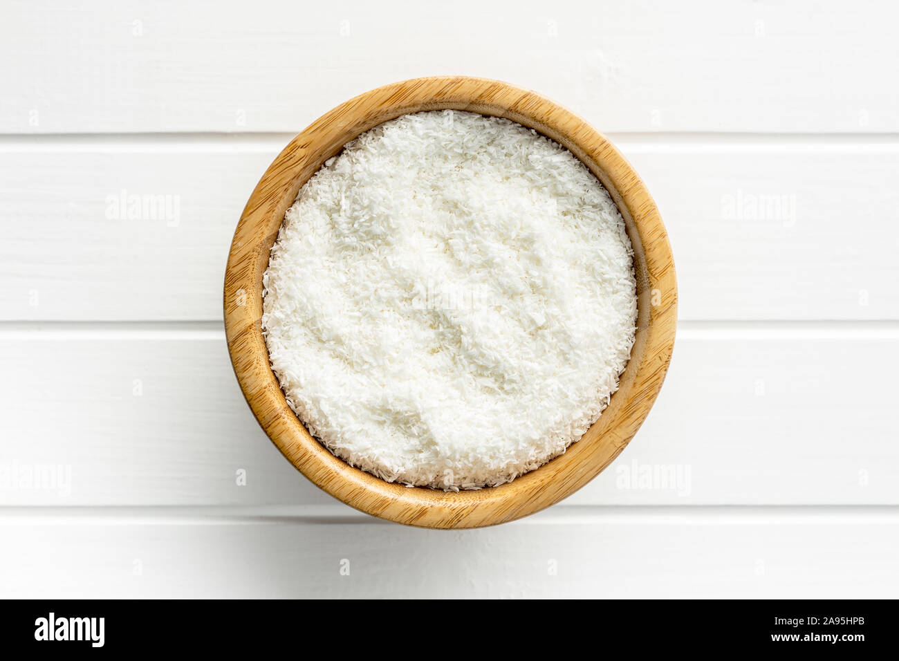 Noix de coco râpée dans le bol sur le tableau blanc. Vue d'en haut. Banque D'Images