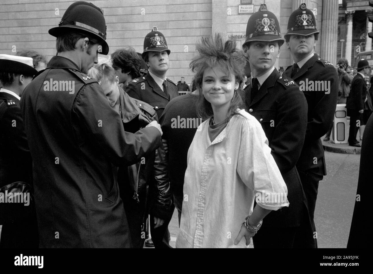 Teen girl Punk des années 80, à l'arrêt de la ville de Londres Royaume-uni 27 septembre 1984 démonstration. Protestation contre le capitalisme anti banquiers 80s en Angleterre. La réalisation d'une police d'arrêter et de recherche sur les jeunes. Girl Friend posing. HOMER SYKES Banque D'Images