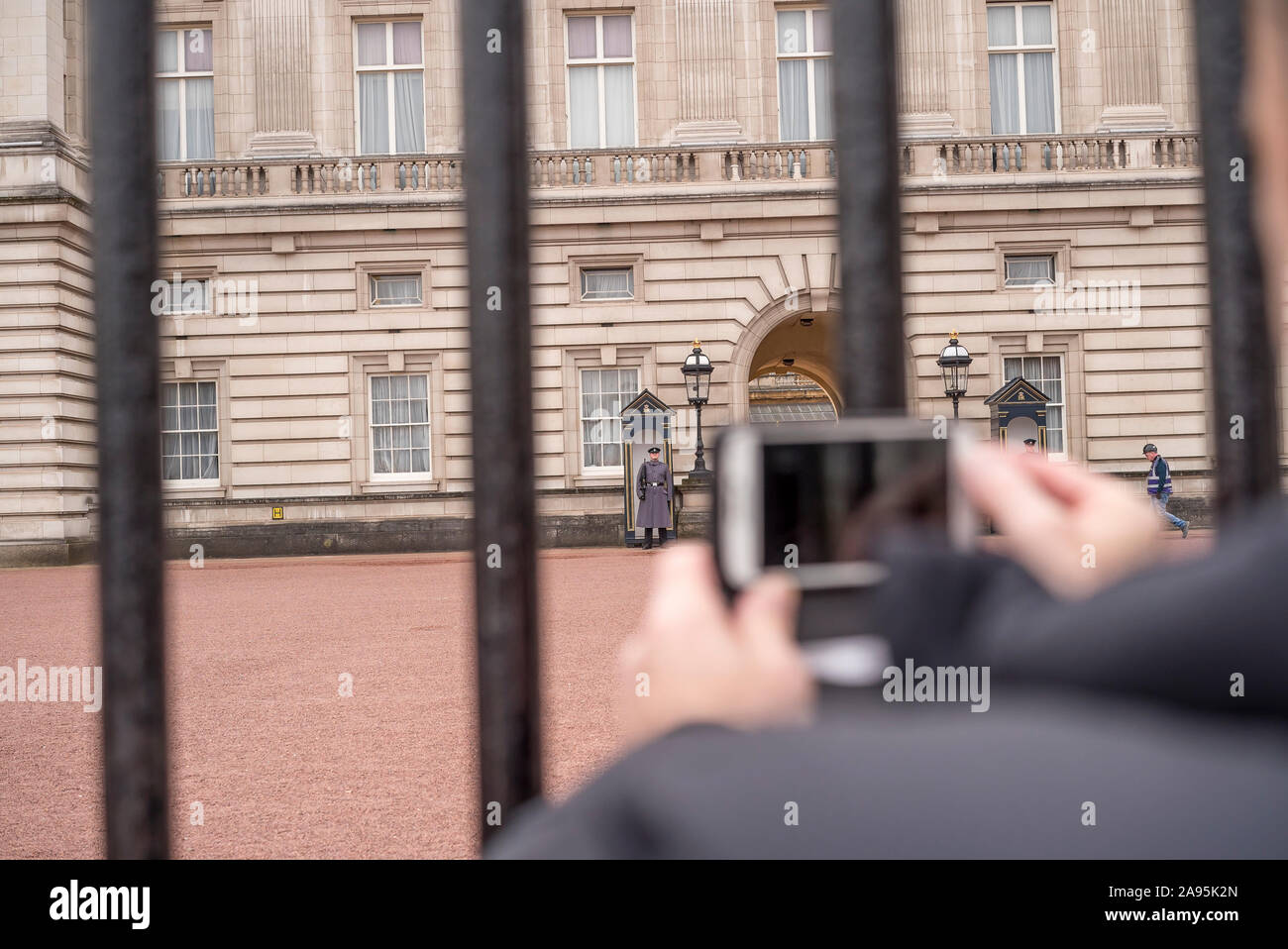 Homme touriste à l'extérieur du palais de Buckingham porte prendre la photo avec son téléphone mobile de la Garde de la Reine en service dans des boîtes de sentry garant le monarque royal. Banque D'Images