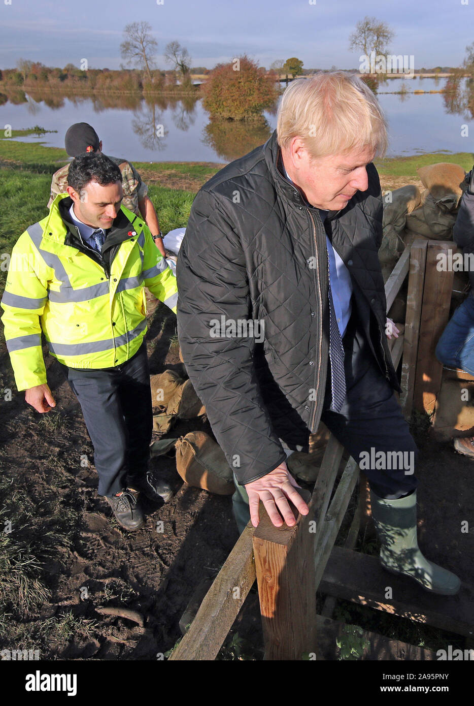 Oliver Harmar, Yorkshire Directrice de secteur de l'Agence de l'environnement, des montres Premier ministre Boris Johnson escalader une clôture au cours d'une visite à Stainforth, Doncaster, à voir les récentes inondations. Banque D'Images