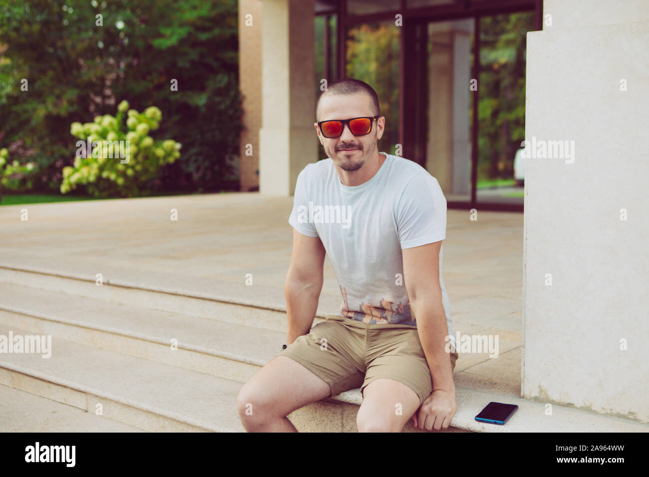 L'Homme à lunettes à la caméra en assis sur les escaliers près du bâtiment Banque D'Images