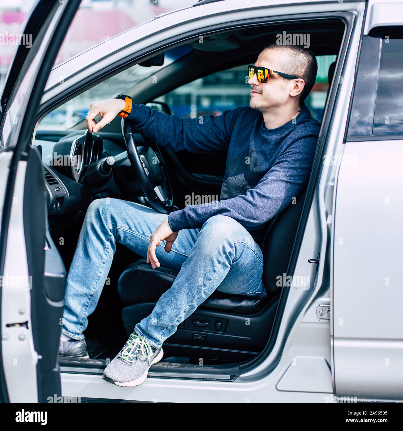 Pilote souriant homme assis dans la voiture avec porte ouverte Banque D'Images