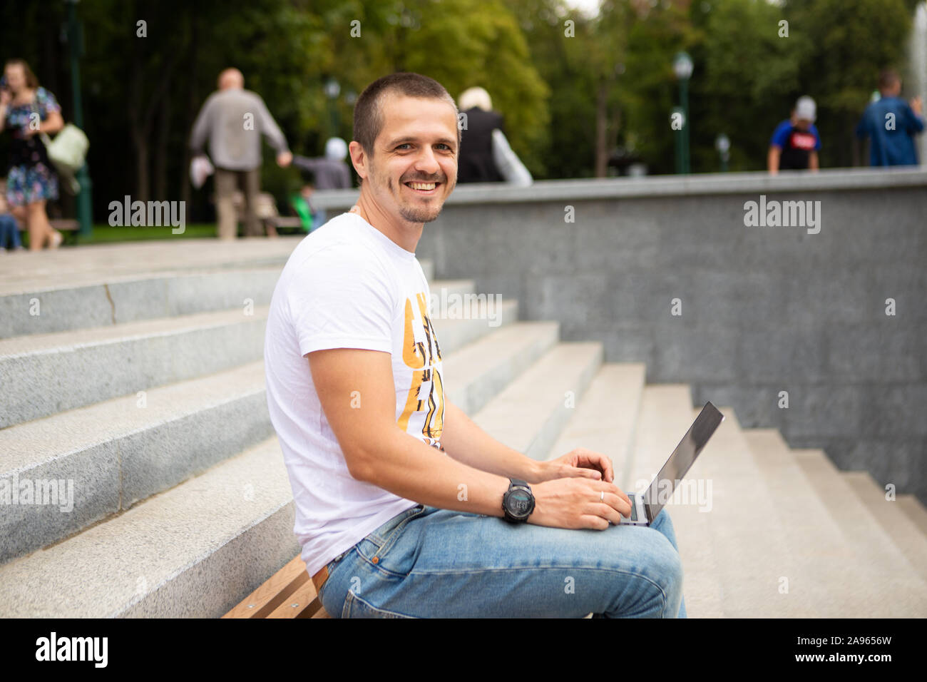 L'homme indépendant avec laptop sitting in urban park Banque D'Images