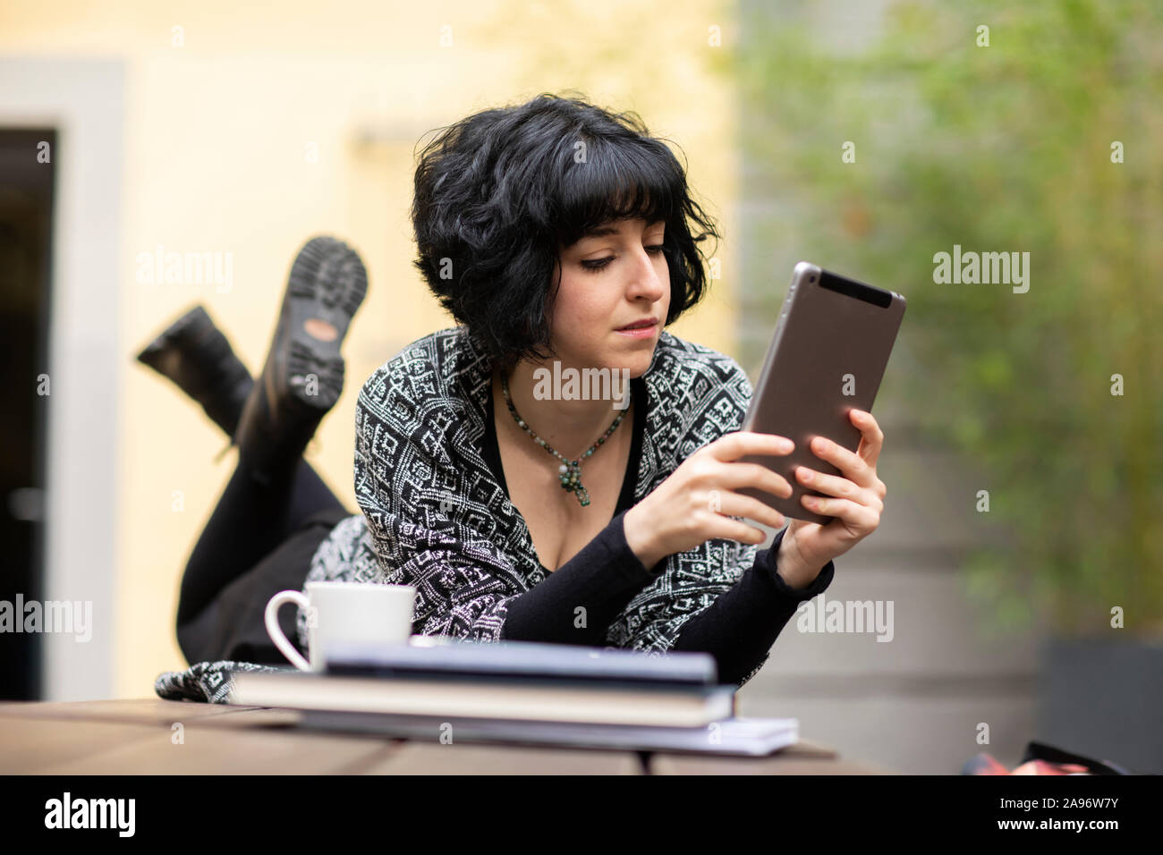 Jeune femme avec un ordinateur portable à l'extérieur et de travail allongé sur une table Banque D'Images