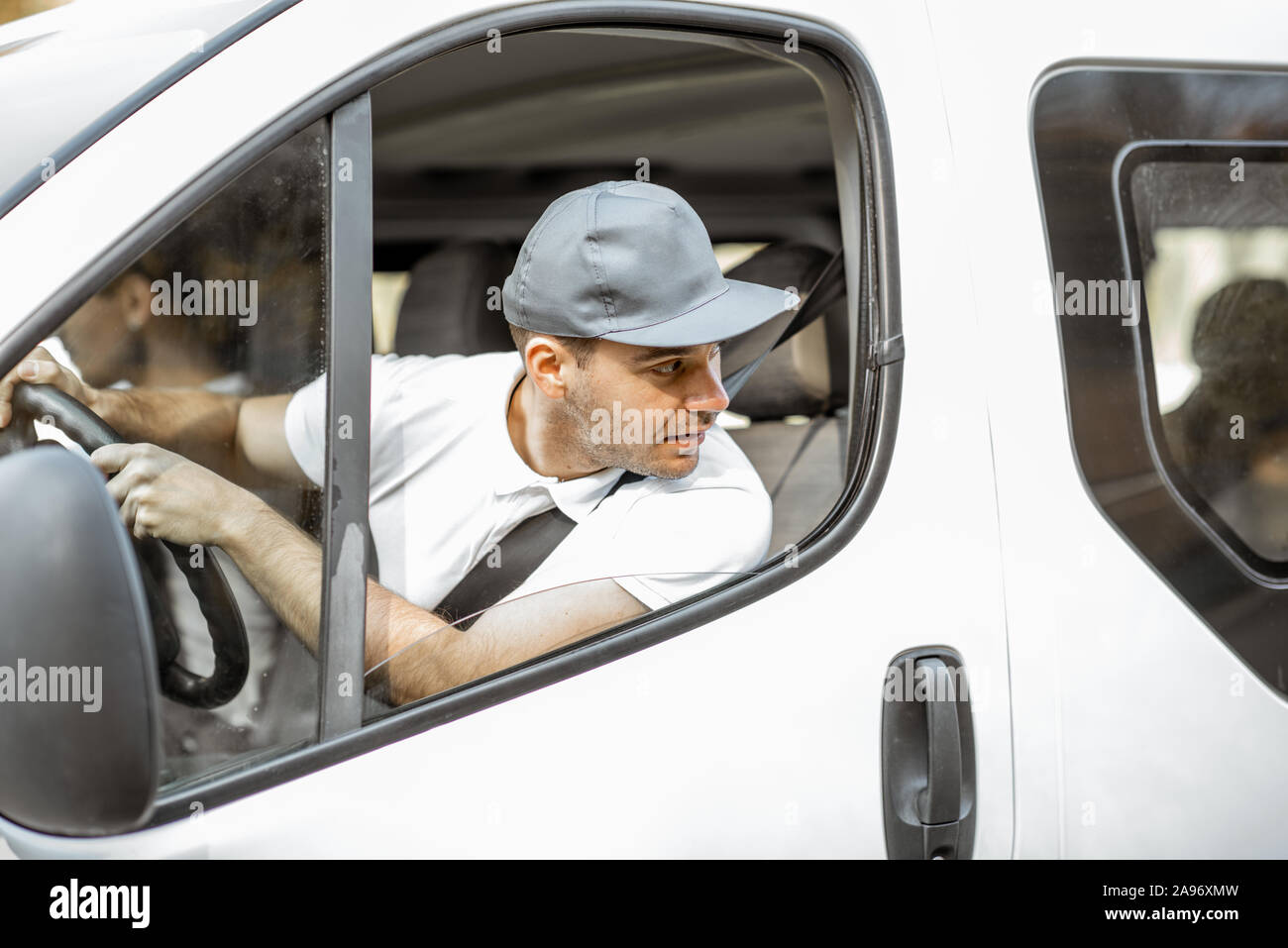 Employé de la compagnie de livraison en uniforme blanc conduite cargo van véhicule alors que la livraison des marchandises à un client Banque D'Images