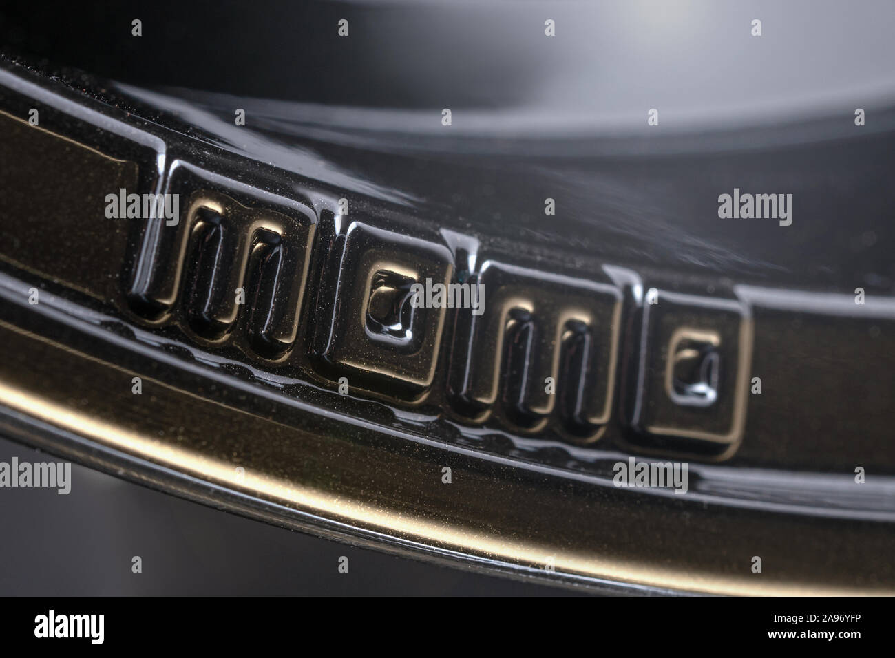 Krasnoyarsk, Russie, le 25 octobre 2019 : voiture logo Momo jantes en alliage, le sport noir léger léger, noir sur fond sombre, Close up. Banque D'Images