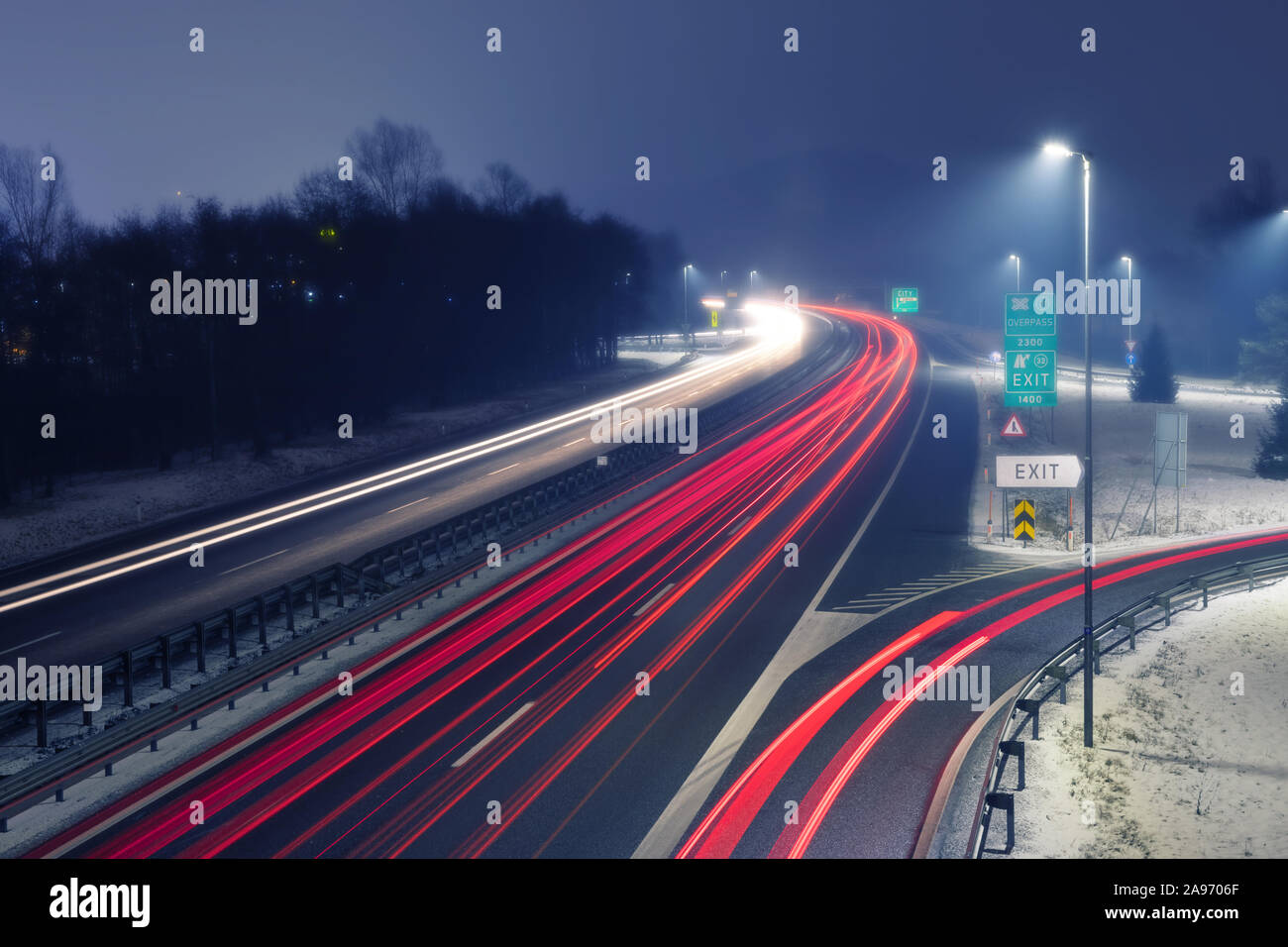 L'autoroute dans la nuit brumeuse avec sentiers lumineux de la lumière de trafic entrant et sortant. Les transports, l'urbanisme, de la circulation et de l'infrastructure des concepts. Banque D'Images