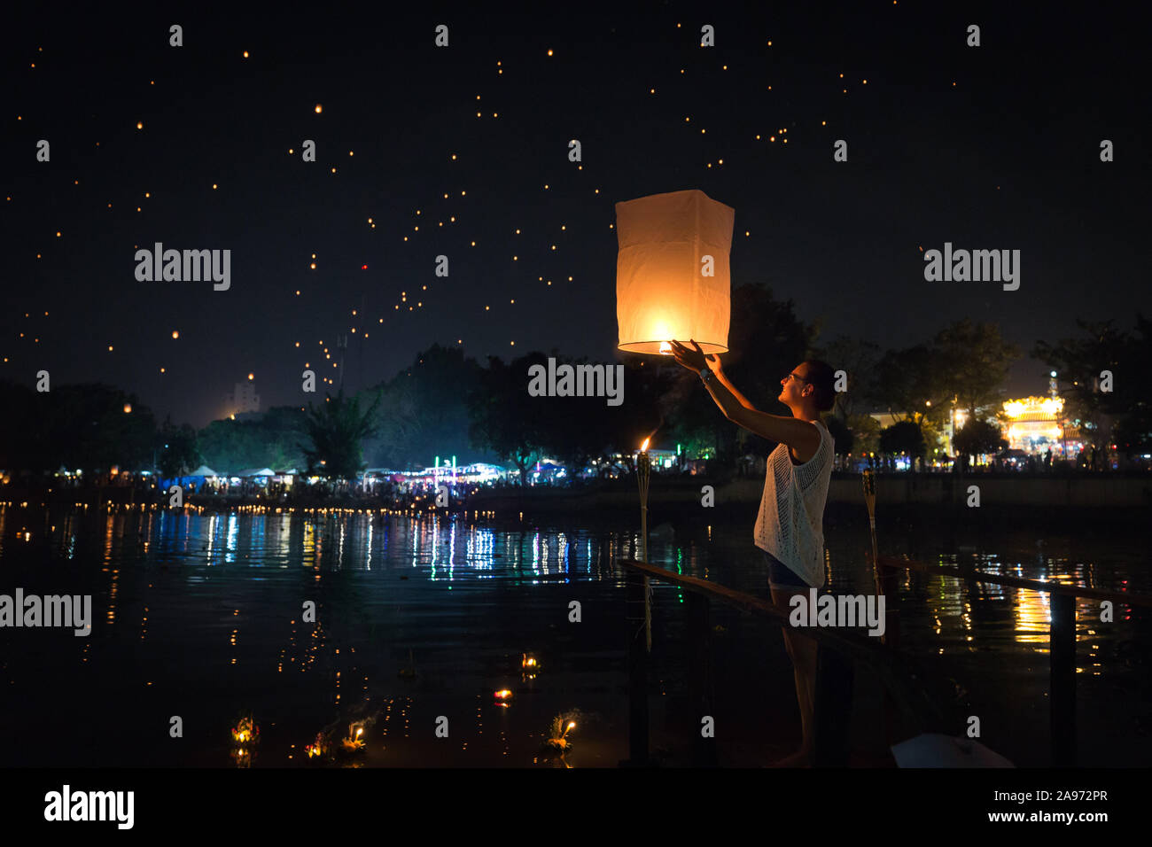 Une femme va communiqué une lanterne sur un pont en bambou au bord de la rivière Ping lors de Chiang Mai Fête des lanternes Banque D'Images
