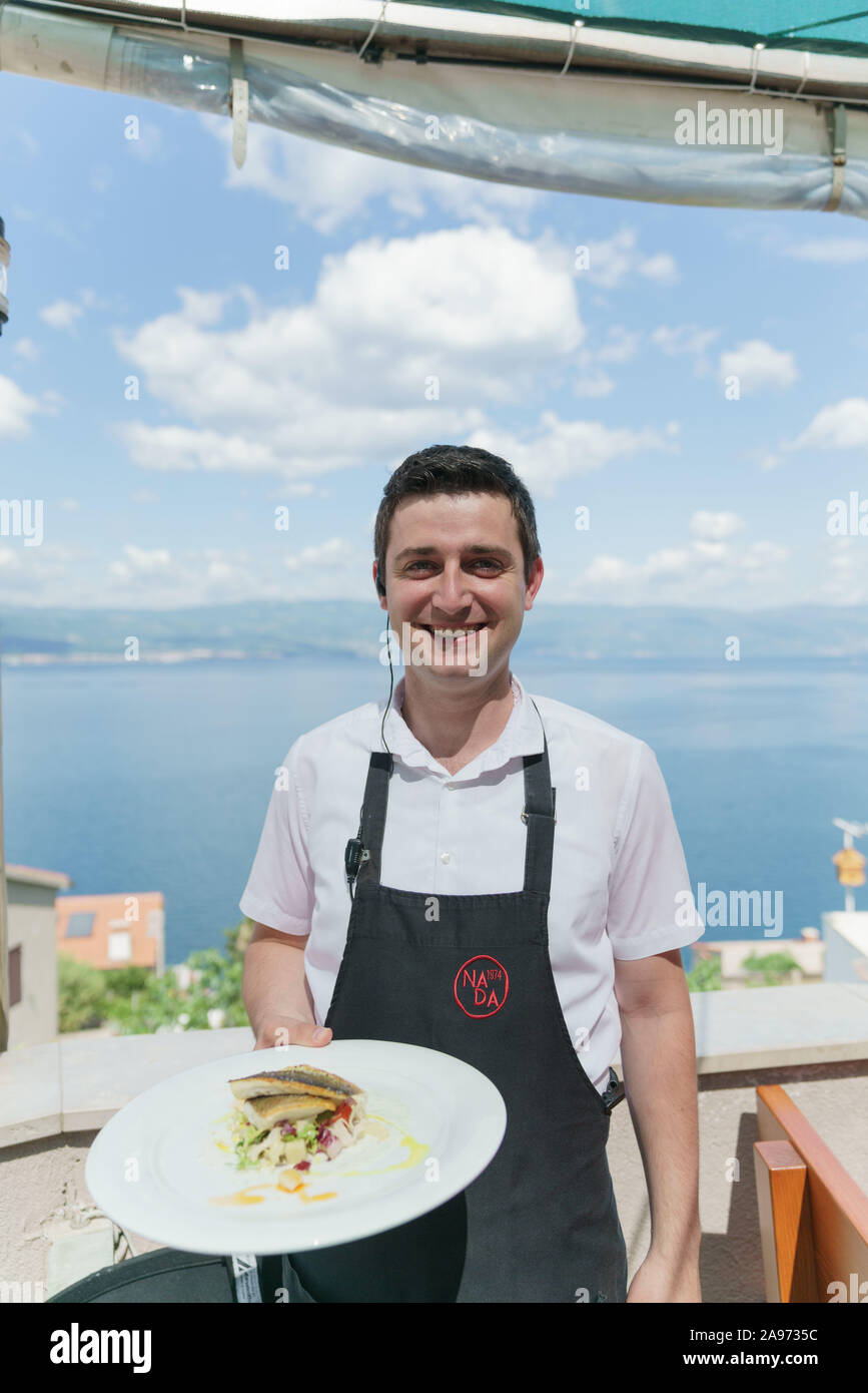 Garçon avec une plaque, Konoba Nada, sur l'île de Krk, Croatie Banque D'Images