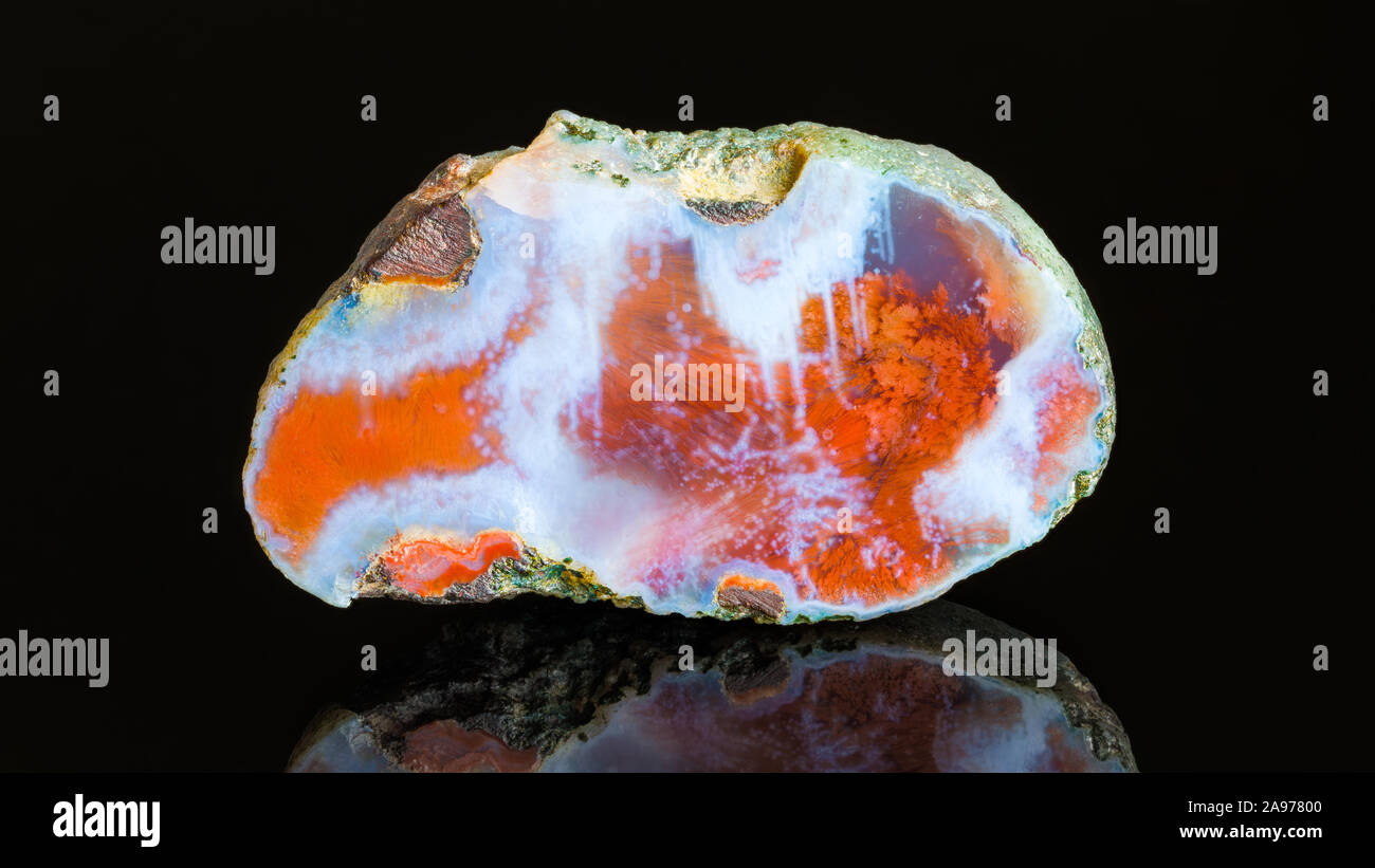 Pierre précieuse d'agate polie section transversale et réflexion sur fond noir. Blanc bleu gemstone détail, marron rouille taches fibreuses sur surface lisse. Banque D'Images