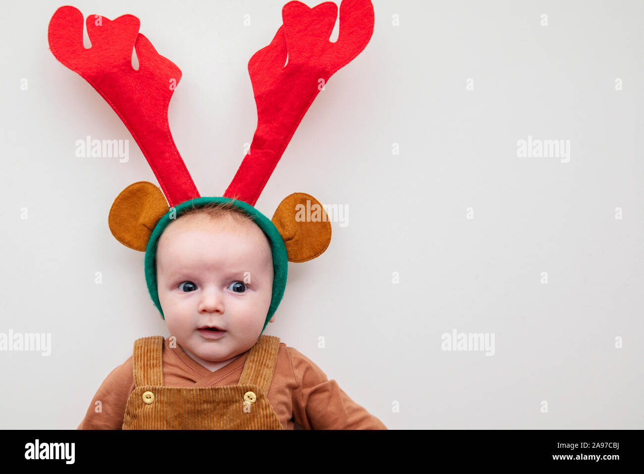 Un mignon petit bébé de deux mois de noël portant des bois de renne Banque D'Images