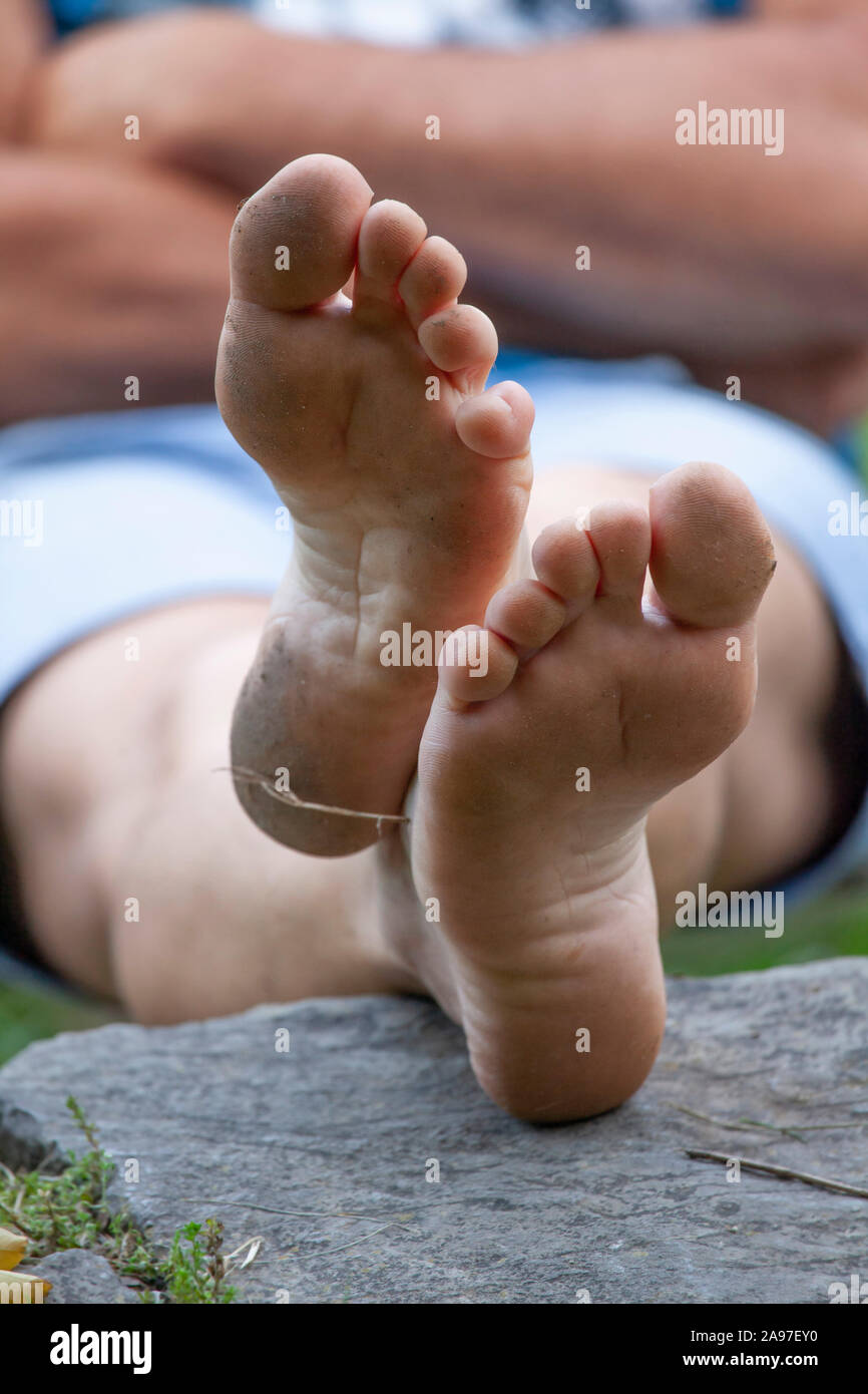 Homme assis aux pieds nus et de détente au bord de la rivière Banque D'Images
