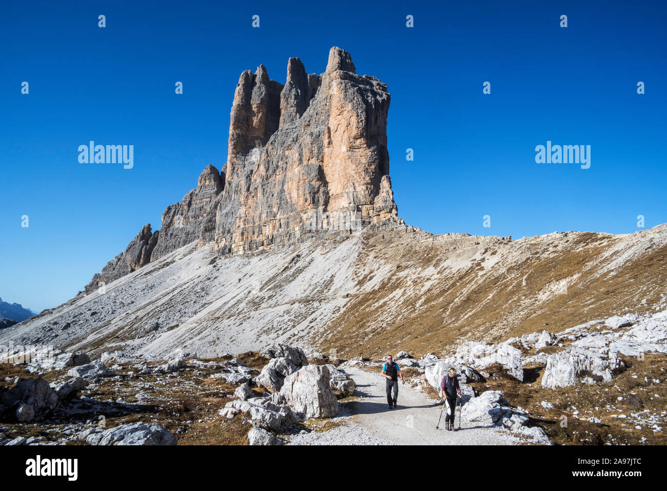 Deux touristes marcher sous la face sud de Tre Cime di Lavaredo / Drei Zinnen, des pics de montagne dans les Dolomites de Sexten, Sesto / Tyrol du Sud, Italie Banque D'Images