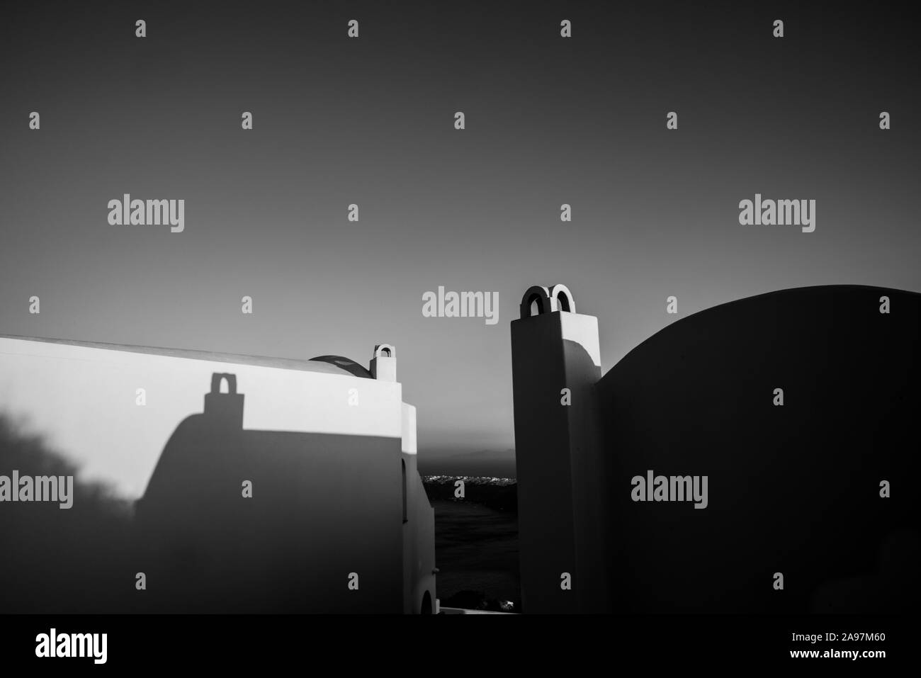 Lever du soleil de Santorin se répercute sur les lignes d'architecture typique de l'immeuble voisin en raison de la ligne de toit incurvé et cheminée en monochrome Banque D'Images