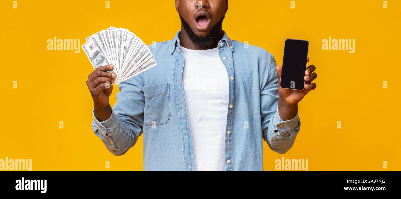 Portrait of African man holding Smartphone avec écran noir et tas d'argent, panorama avec l'espace vide Banque D'Images