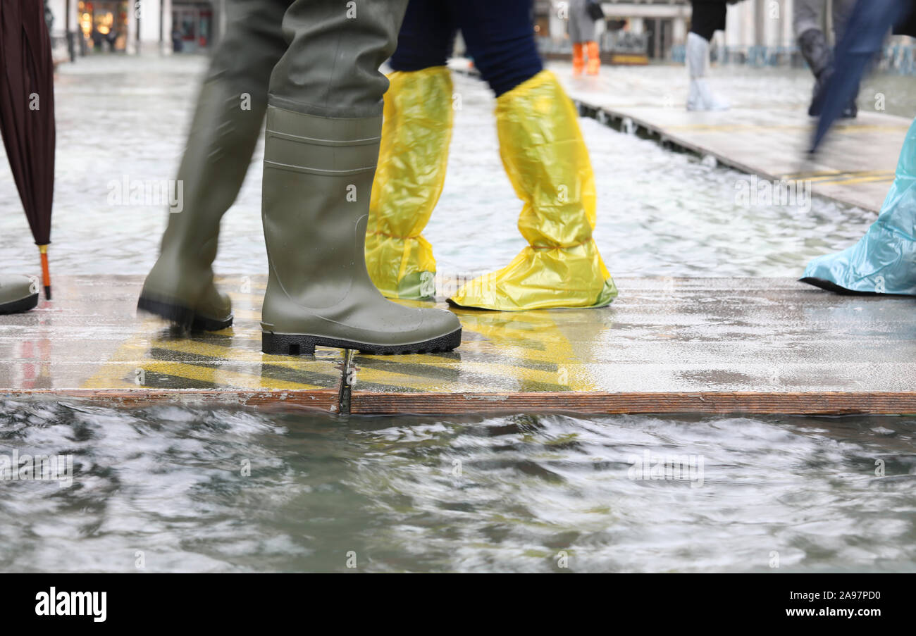 Les gens avec des bottes en caoutchouc et en plastique à soufflets Venise  Italie au cours de la marée haute Photo Stock - Alamy