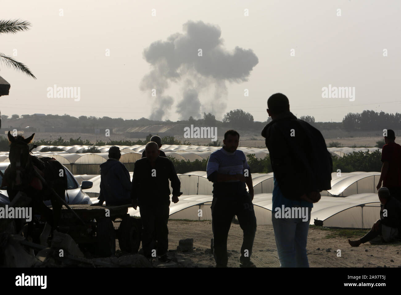 Palestiniens regarder la fumée s'élevant après une frappe aérienne israélienne à Khan Younis dans le sud de la bande de Gaza, le 13 Nov 2019. Photo par Abed Rahim Khatib Banque D'Images