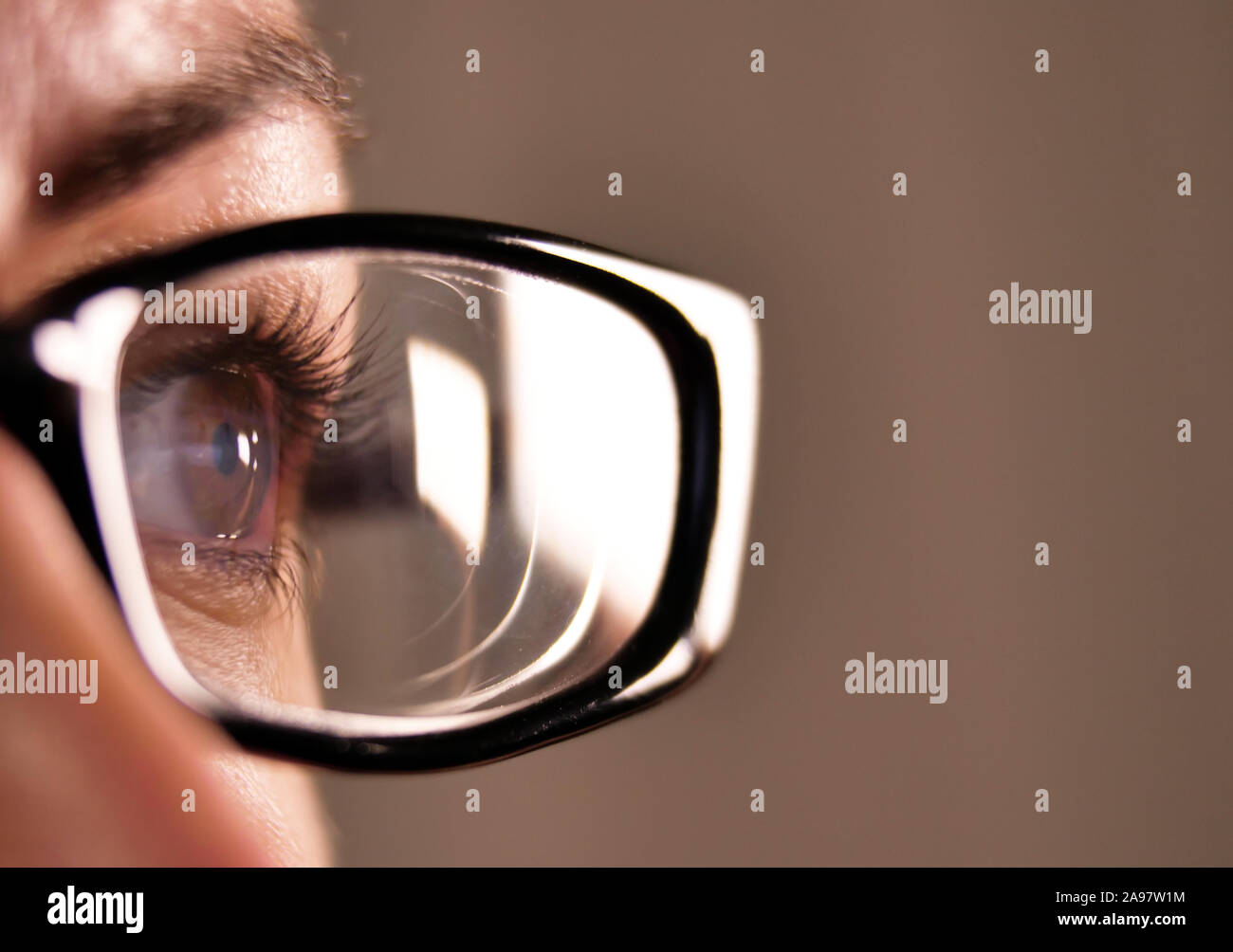 Ouvrez grand les yeux bruns d'une fille avec des lunettes avec un cadre noir sur fond gris Banque D'Images