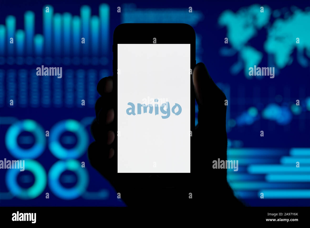 Un homme est titulaire de l'iPhone qui affiche le logo, prêts Amigo tourné contre un style de visualisation de données (fond usage éditorial uniquement). Banque D'Images Un homme est titulaire de l'iPhone qui affiche le logo, prêts Amigo tourné contre un style de visualisation de données (fond usage éditorial uniquement). Banque D'Images