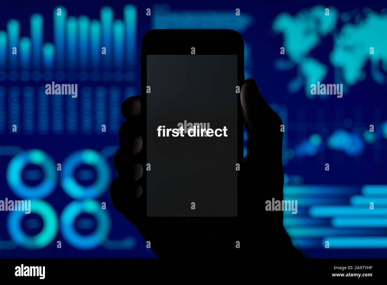 Un homme est titulaire de l'iPhone qui affiche la première banque directe, logo tourné contre un style de visualisation de données (fond usage éditorial uniquement). Banque D'Images