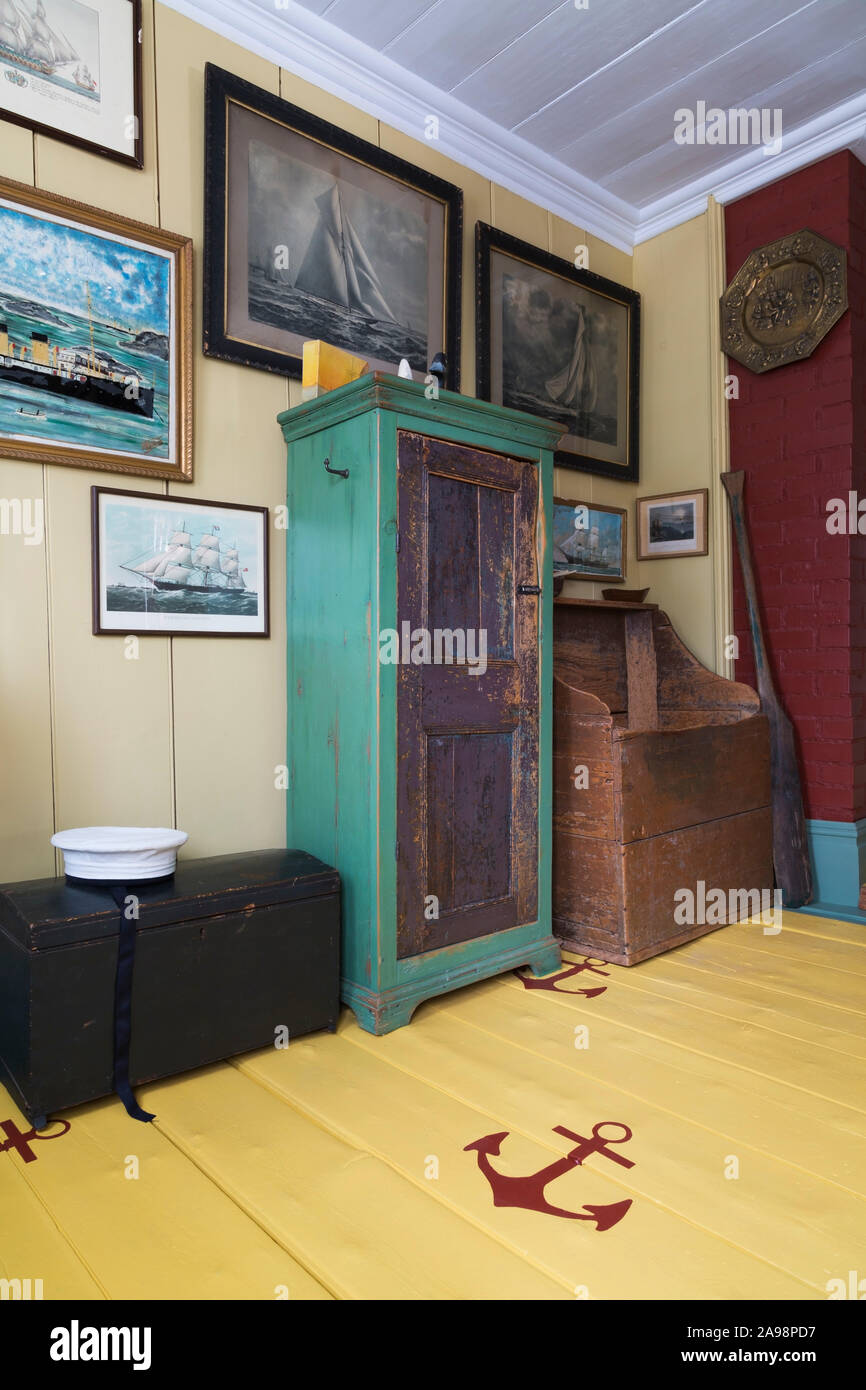 Voilier peintures, Marin's hat, Antique armoire bois et de l'Aviron Aviron en entrée avec des ancres sur les planches peintes en jaune à l'intérieur de vieux 1835 house Banque D'Images