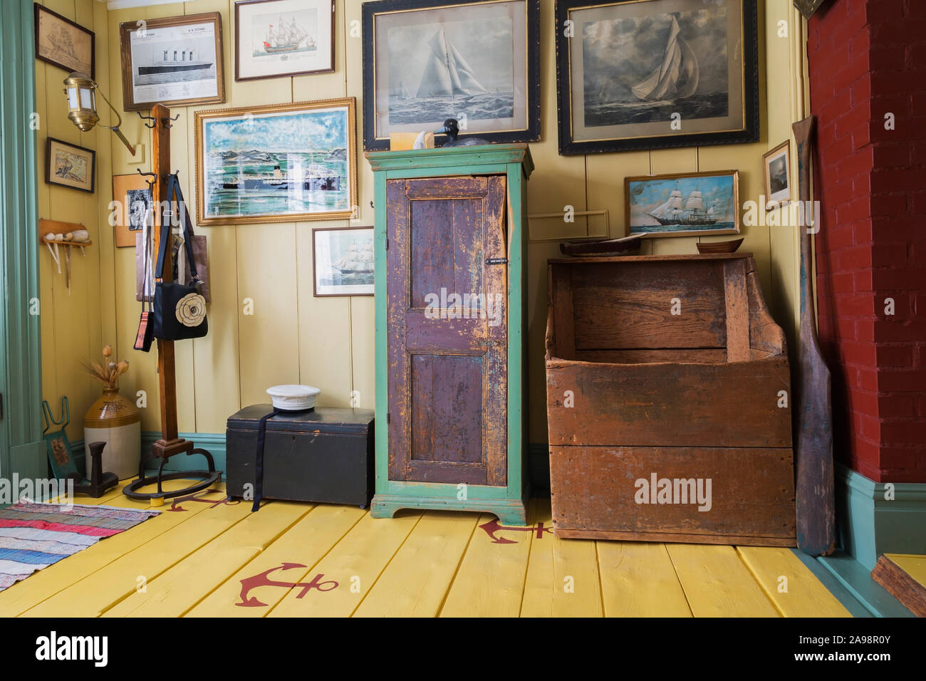 Voilier peintures, Marin's hat, Antique armoire bois et de l'Aviron Aviron en entrée avec des ancres sur les planches peintes en jaune à l'intérieur de vieux 1835 house Banque D'Images