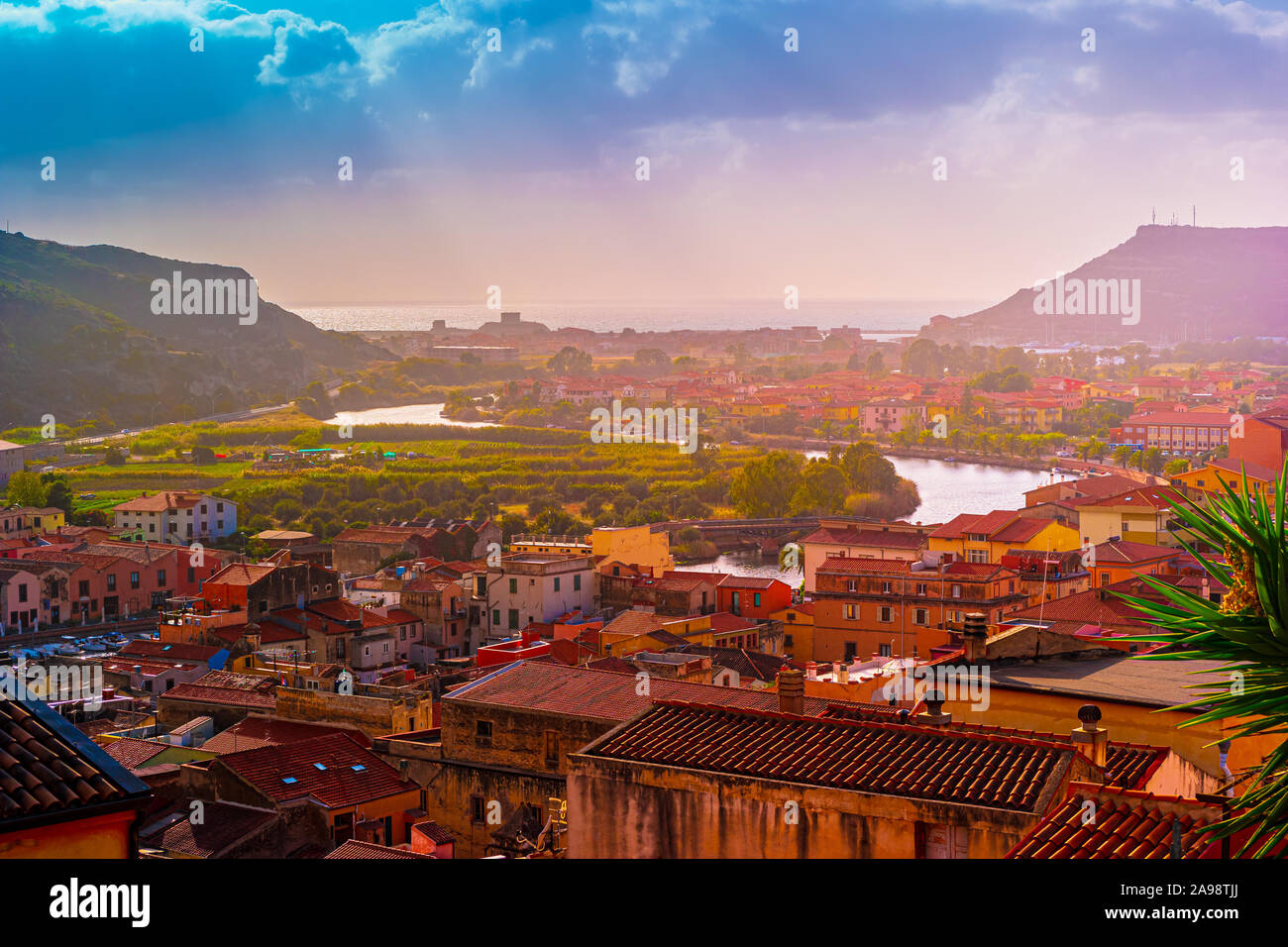 Vue de dessus sur la ville Bosa de maisons aux toits rouges, des montagnes avec des arbres verts et la rivière Temo qui se jettent dans la mer Méditerranée. Location e Banque D'Images