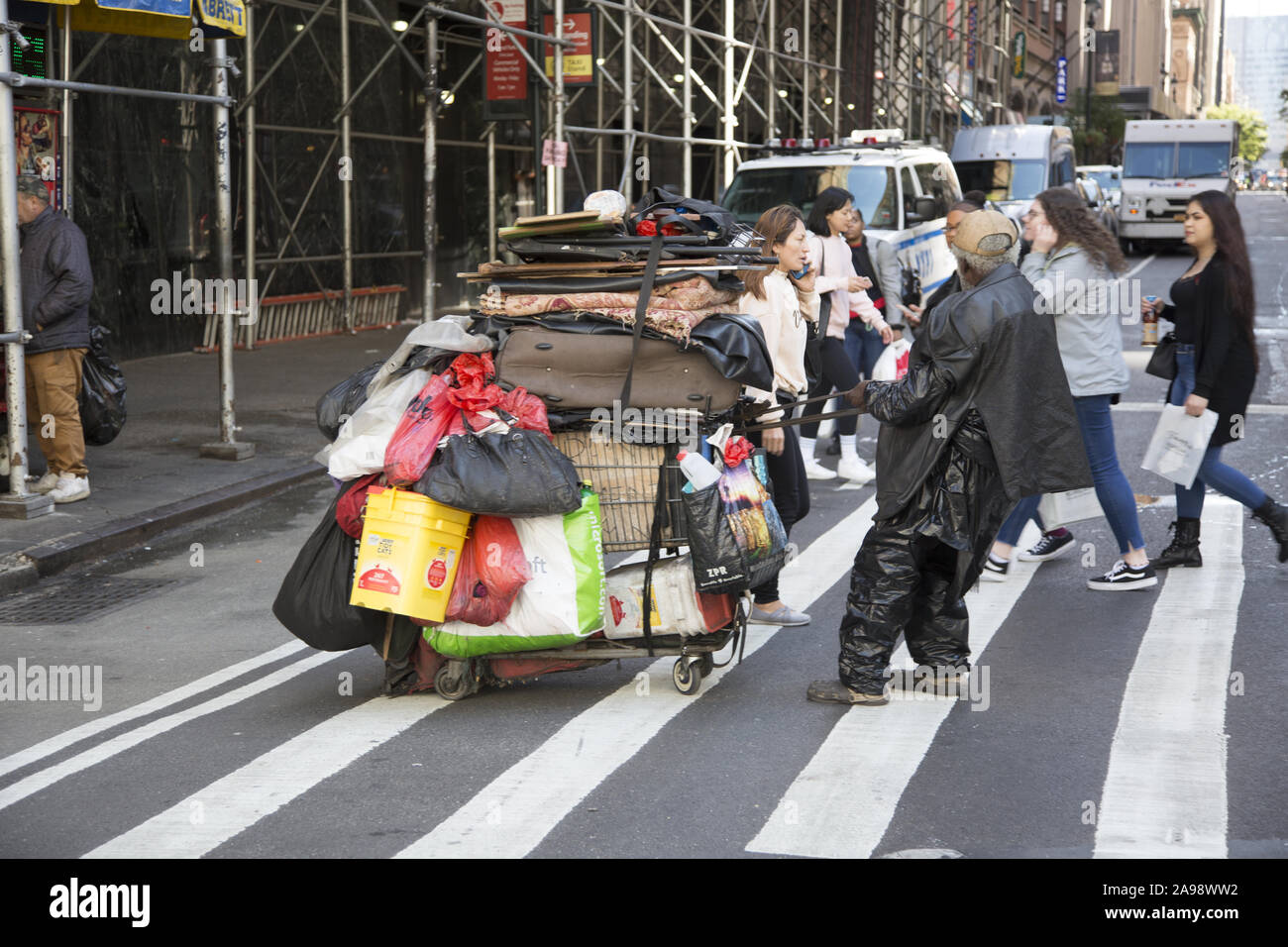 Sans-abri tire un panier rempli de ses choses le long de la 6e Avenue près de la 34e rue à Manhattan, New York City. Banque D'Images