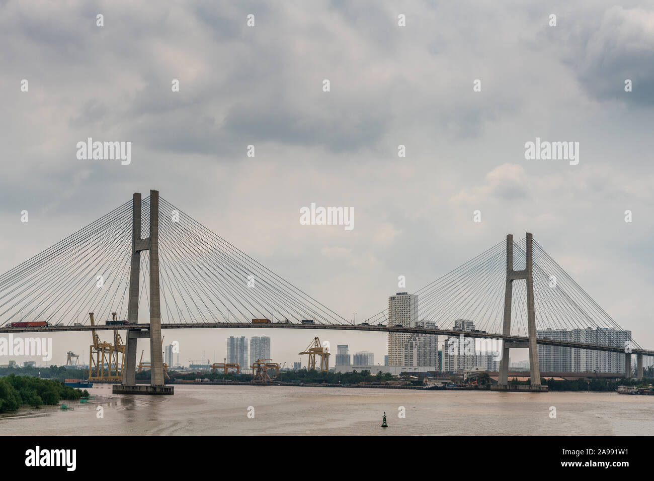 Ho Chi Minh Ville, Vietnam - 12 mars 2019 : chanson fleuve Sai Gon. Phu My bridge avec ses 2 pylônes de suspension dans l'eau brune sous la lumière cloudscape bleu. Banque D'Images