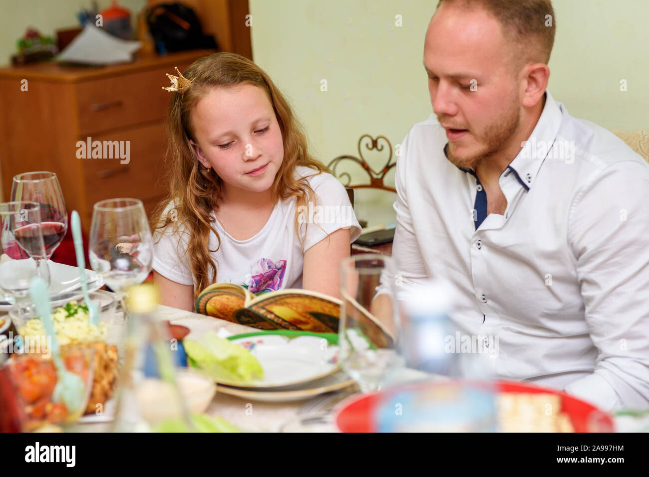 La lecture de la Haggada, famille juive à la fête de Pâque. Selective focus on jolie fille. Banque D'Images