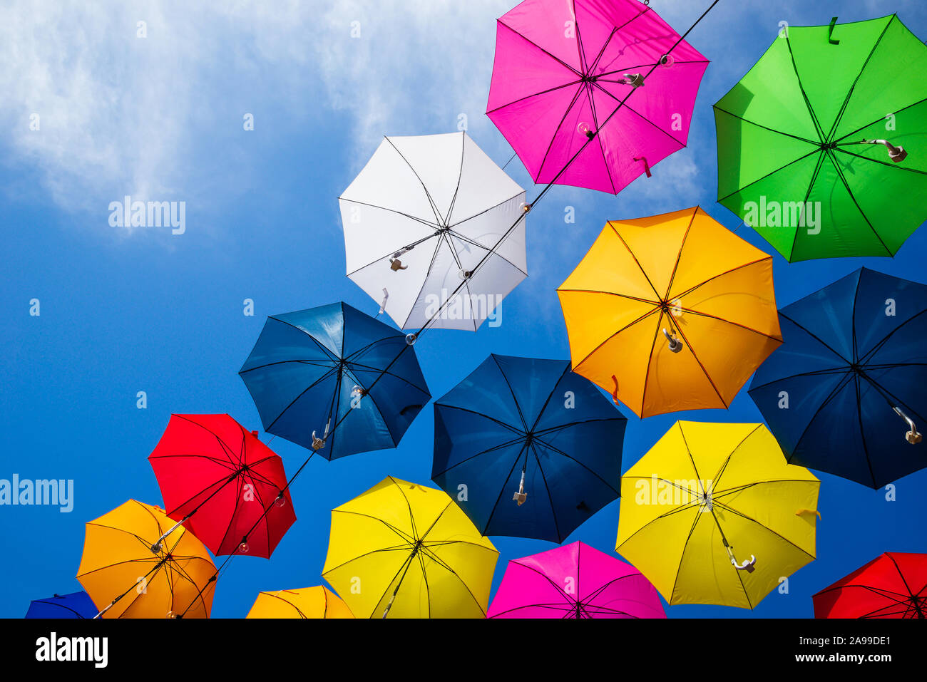 Bel ensemble de parasols colorés au-dessus de la rue contre le ciel bleu sur une journée ensoleillée Banque D'Images