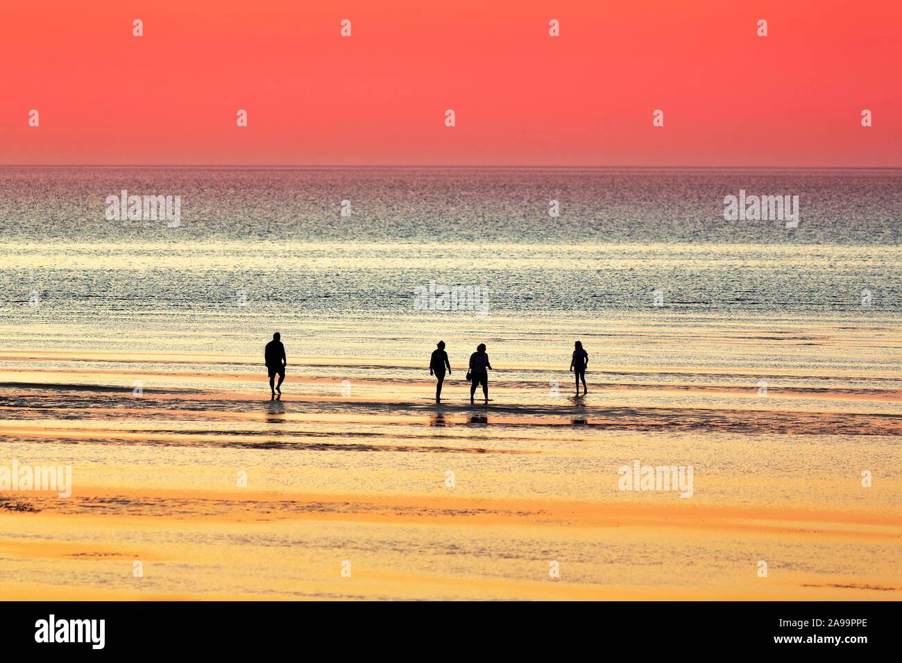 Silhouettes de personnes sur la plage dans la mer au coucher du soleil, de la mer du Nord, Basse-Saxe, Allemagne Banque D'Images