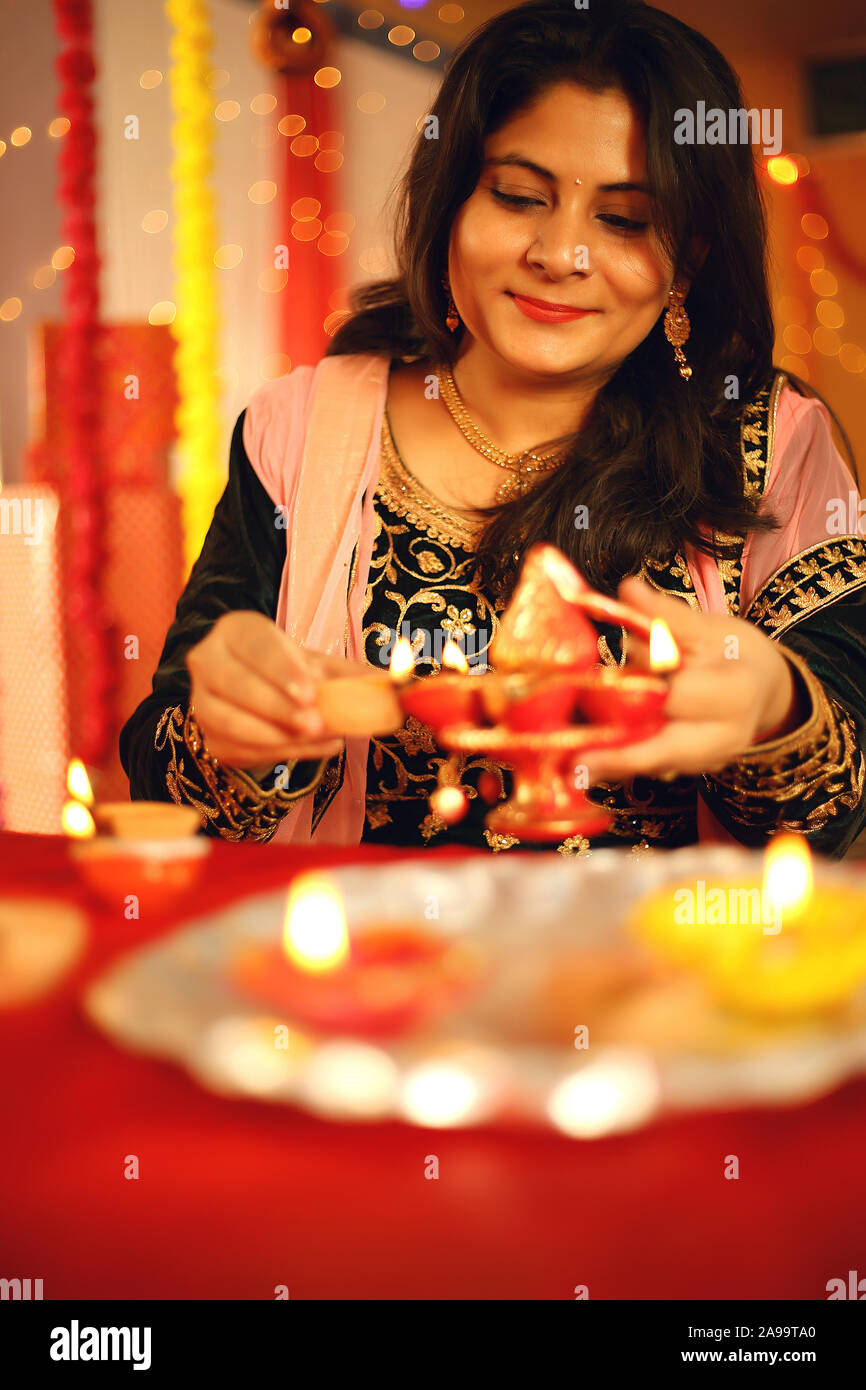 Une belle jeune femme indienne en sari traditionnel dress holding une lampe à huile légère ou Diya dans l'arrière-plan décoratif à l'occasion de Diwali Banque D'Images