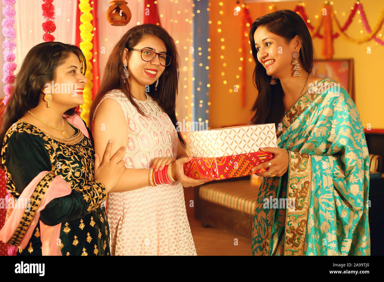 Jolies jeunes femmes indiennes portant des vêtements ethniques traditionnels cadeau donner à une femme, plus de flou d'arrière-plan de fête. Banque D'Images