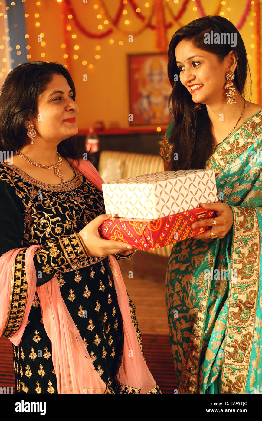 Jolie jeune femme indienne portant des vêtements ethniques traditionnels cadeau donner à une femme, plus de flou d'arrière-plan de fête. Banque D'Images