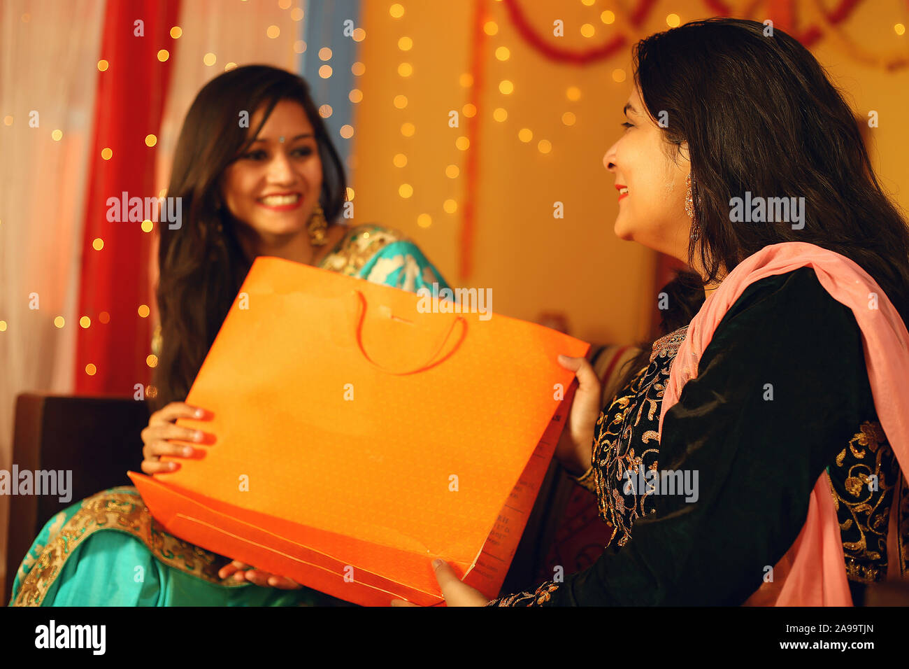 Jolie jeune femme indienne portant des vêtements ethniques traditionnels cadeau donner à une femme, plus de flou d'arrière-plan de fête. Banque D'Images