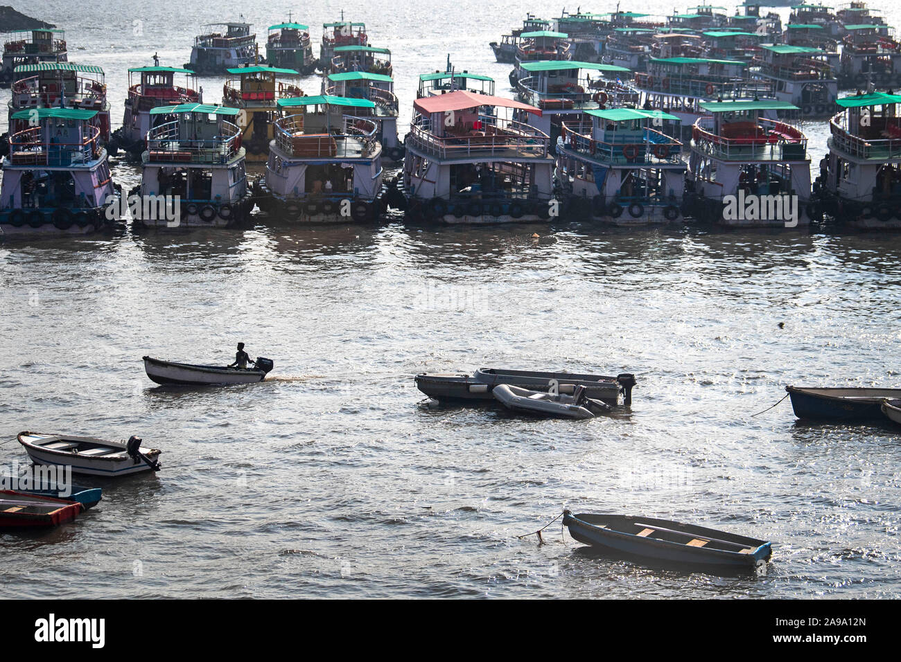 Un matin tôt pêcheur traverse un port rempli de bateaux dans Mumbai, Inde, comme Prince de Galles continue sa tournée en Inde. Banque D'Images