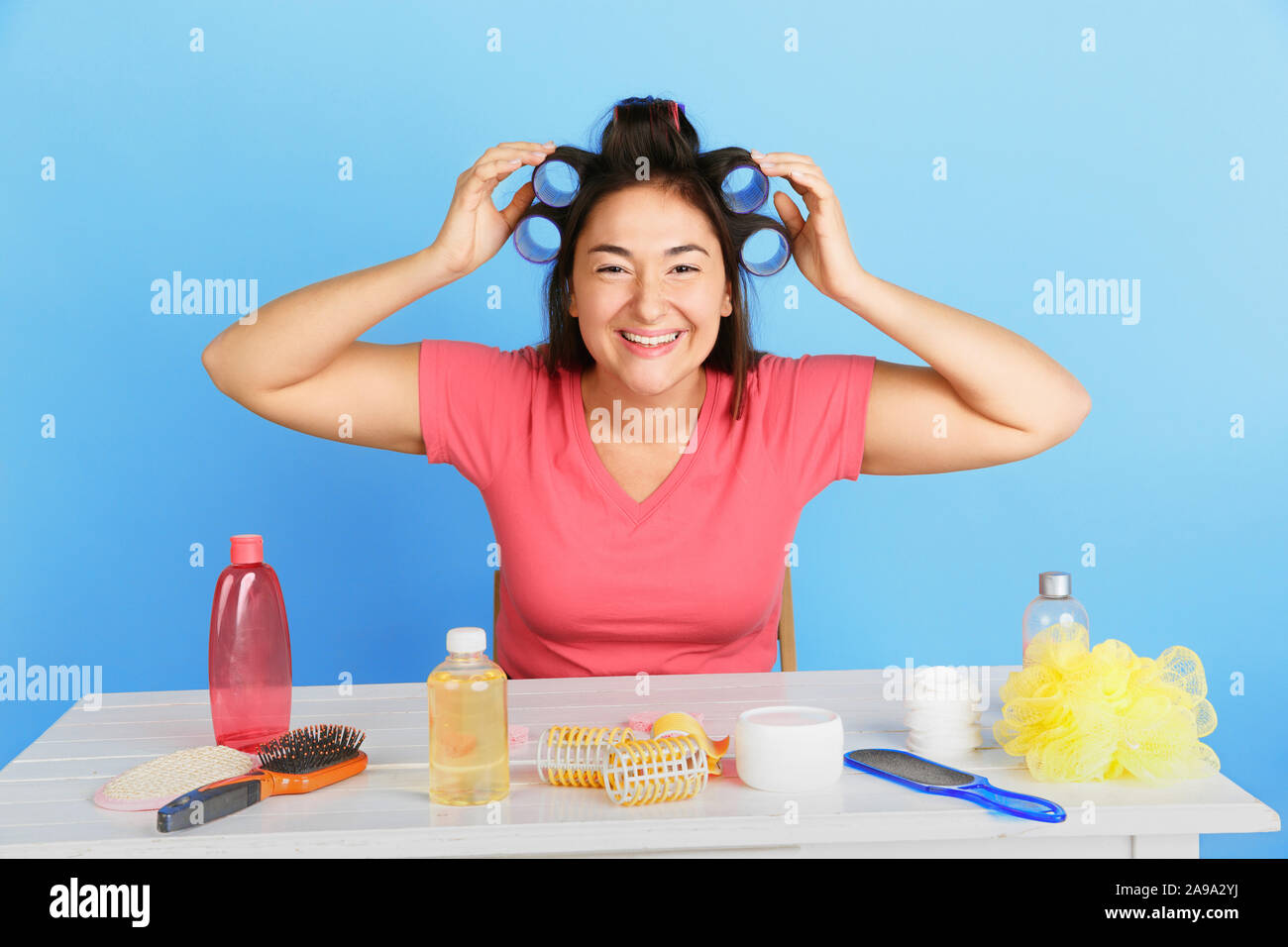 Portrait of young woman in her beauty jour et soins quotidiens de la peau. Modèle féminin avec les produits cosmétiques naturels d'appliquer la crème et huiles essentielles pour rattraper, coiffure. Soins corps et visage, beauté naturelle concept. Banque D'Images