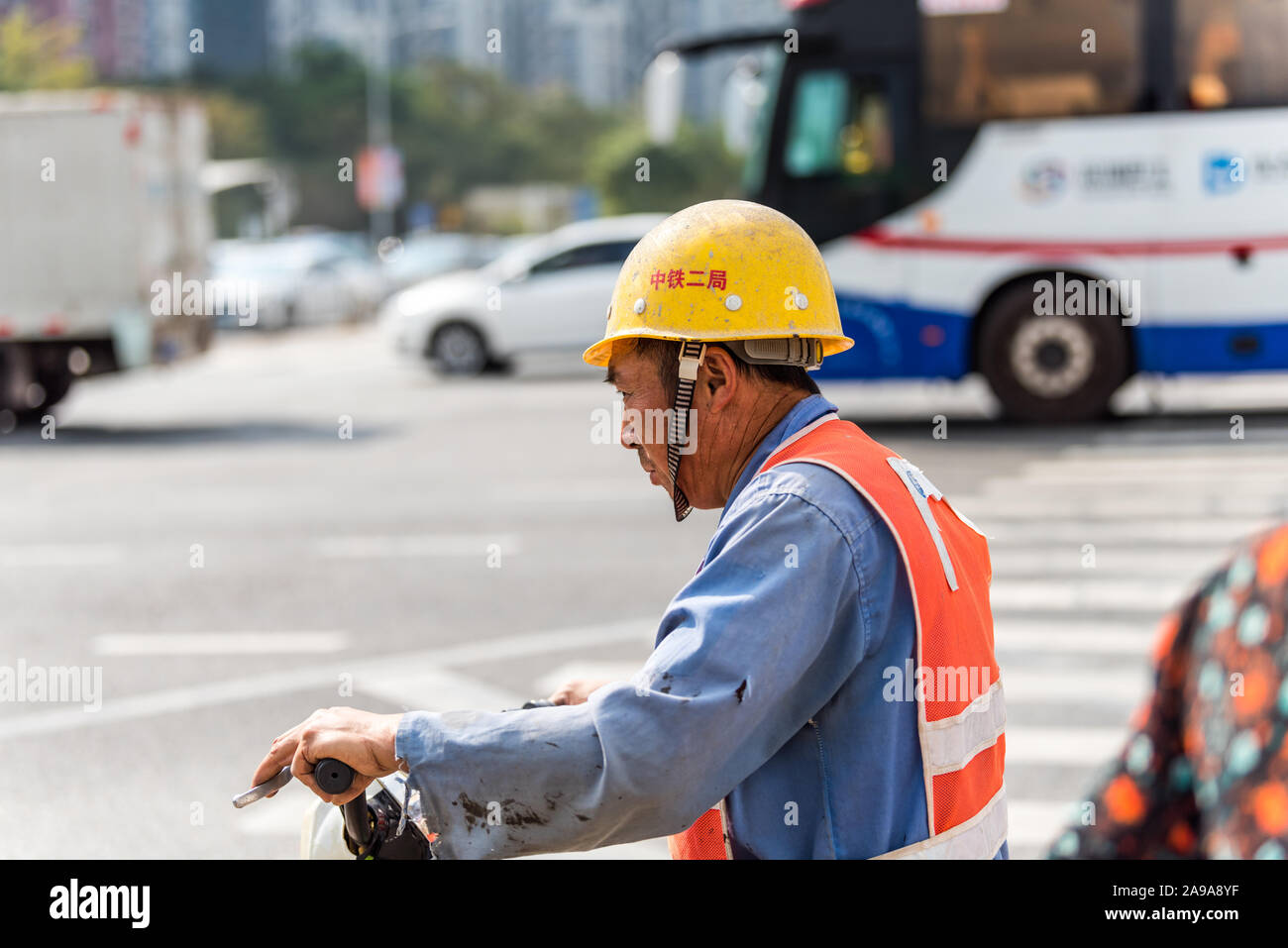 Un travailleur de la construction le port de casque de sécurité au volant d'un scooter à la rue de Shenzhen, Chine. Banque D'Images