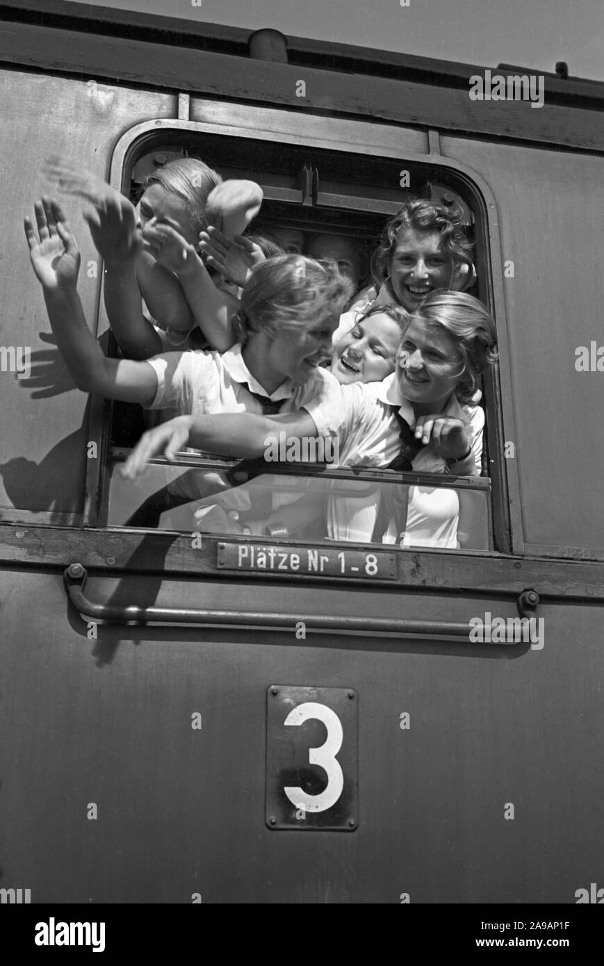 Filles oout BdM acclamations de la fenêtre de leur train de les prendre à leurs vacances, Allemagne 1930. Banque D'Images