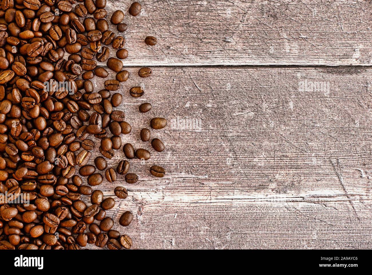 Les grains de café torréfiés brun foncé sur arrière-plan du tableau de bois patiné rustique avec beaucoup d'espace de copie. Vue d'en haut. Banque D'Images