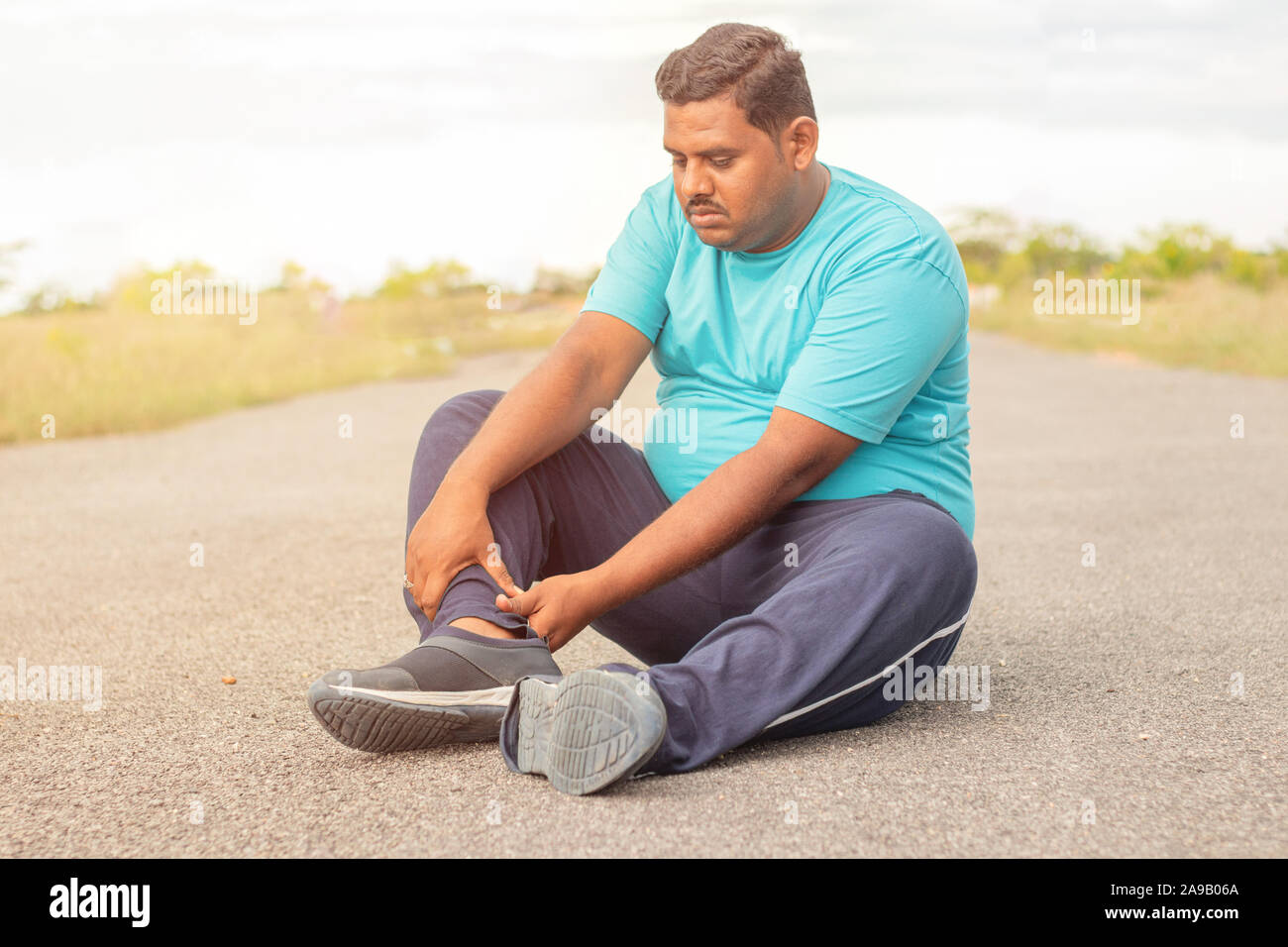 Concept de tendon de la jambe de Fat Man - personne obèse souffrant de douleurs musculaires de la jambe de portefeuille - l'excès de l'homme au concept de remise en forme parc extérieur. Banque D'Images