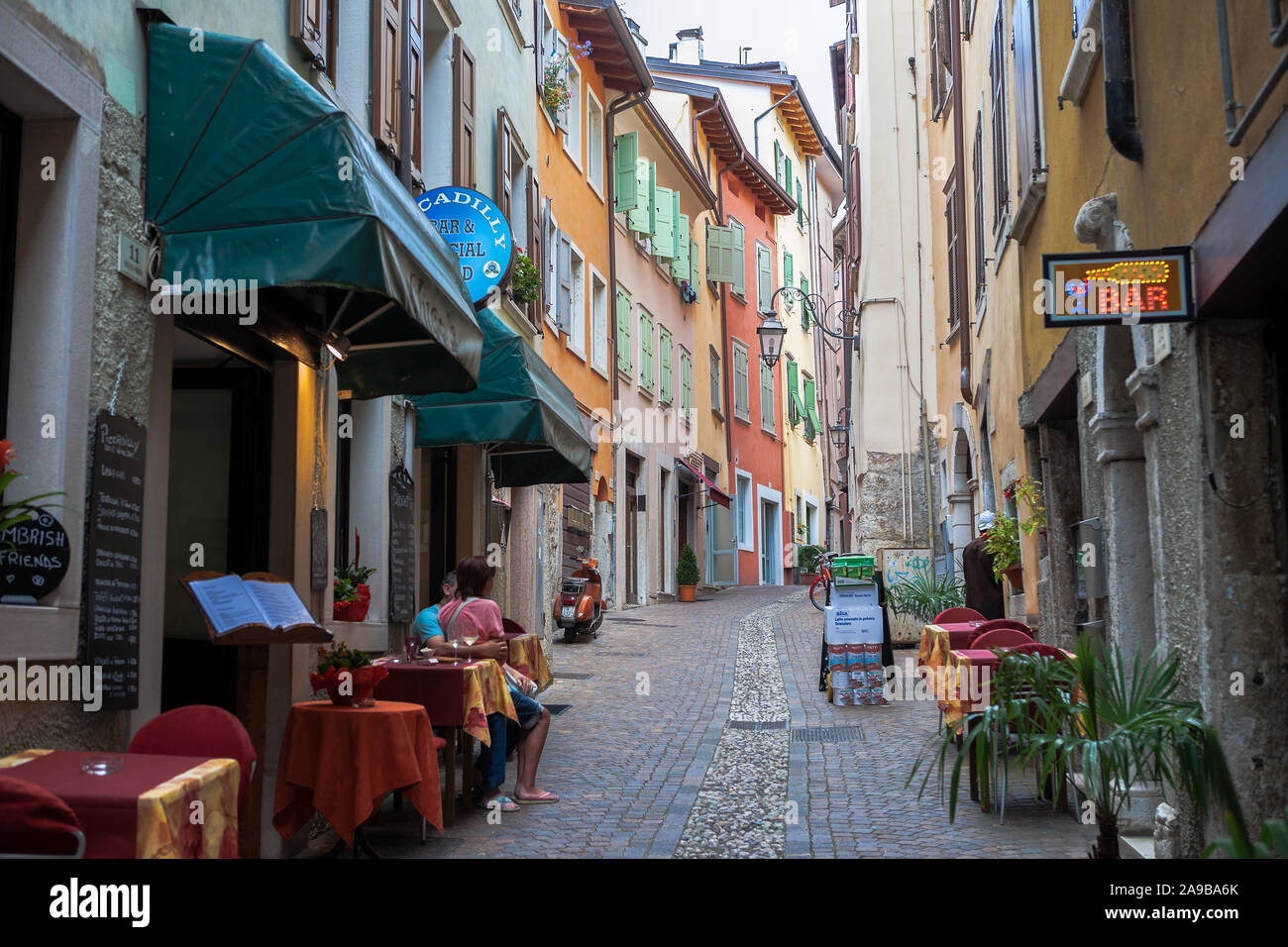 Un couple s'asseoir dans une zone piétonne tranquille, bénéficiant d'une 'All'aperto' apéritif : Via dei Fabbri, Riva del Garda, Trentino, en Italie Banque D'Images