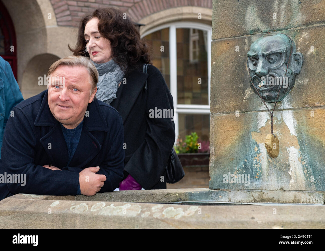 14 novembre 2019, en Rhénanie du Nord-Westphalie, Münster : l'acteur Axel Prahl (l) s'appuie contre la fontaine en face de la Kiepenkerl, l'emplacement de la nouvelle scène de crime "limbe" à Münster. L'actrice Mechtild Grossmann se tient dans le dos. Photo : Guido Kirchner/dpa Banque D'Images