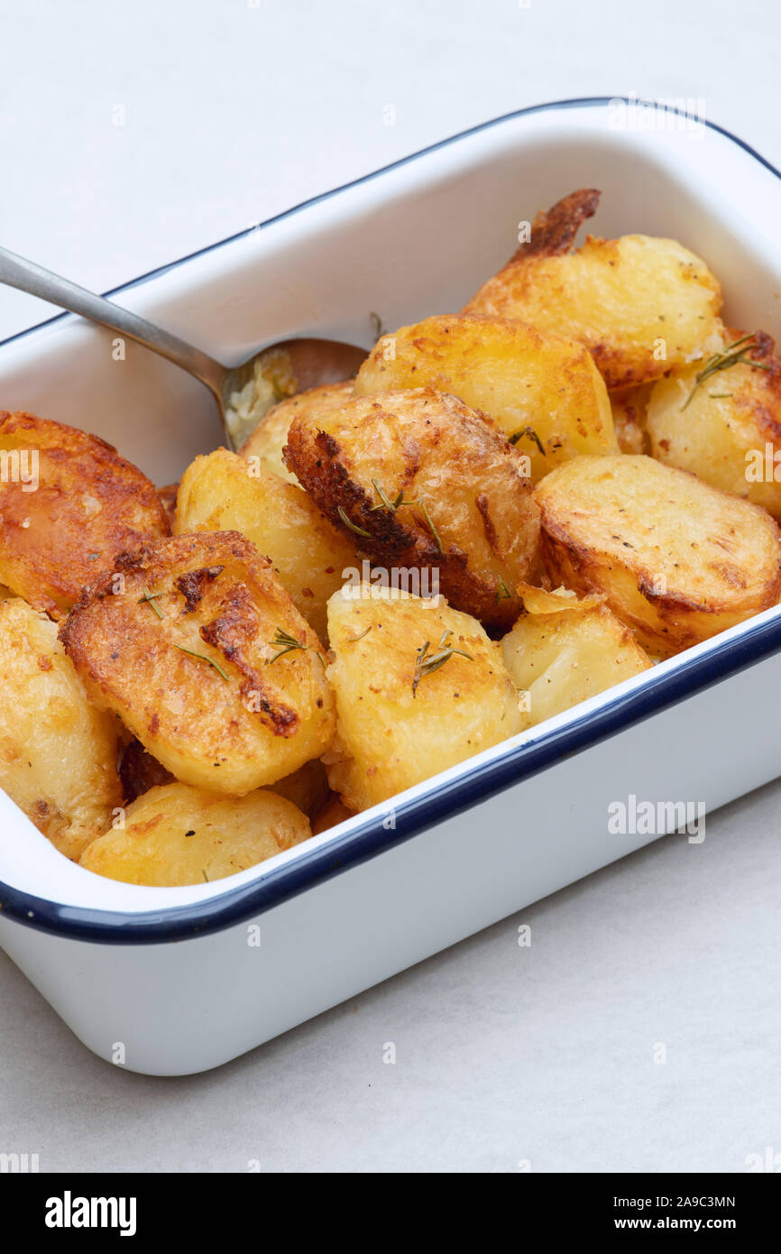 Pommes de terre dans un plat à rôtir en émail blanc sur fond blanc Banque D'Images